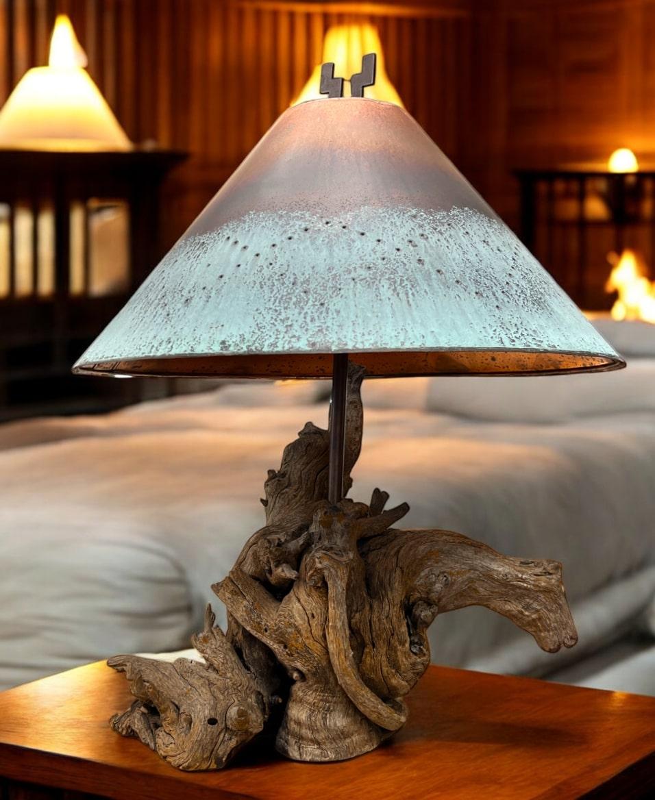 This American Southwest table lamp is a stunning fusion of rustic charm and artistry. The focal point is a unique reticulated copper shade. Its aged patina evokes the rugged beauty of Southwestern landscapes. Complementing the shade is a natural