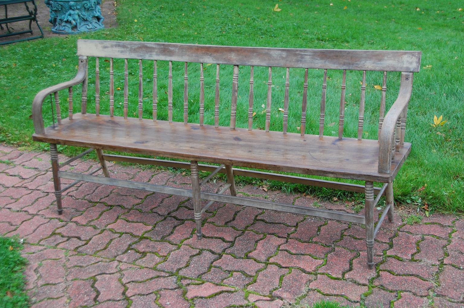 American mid 19th century spindleback bench with remnants of original paint. This six foot long bench has six legs, steam bent arms, interestingly turned spindles, and box stretchers. We have gone over this handsome bench and made sure that all of