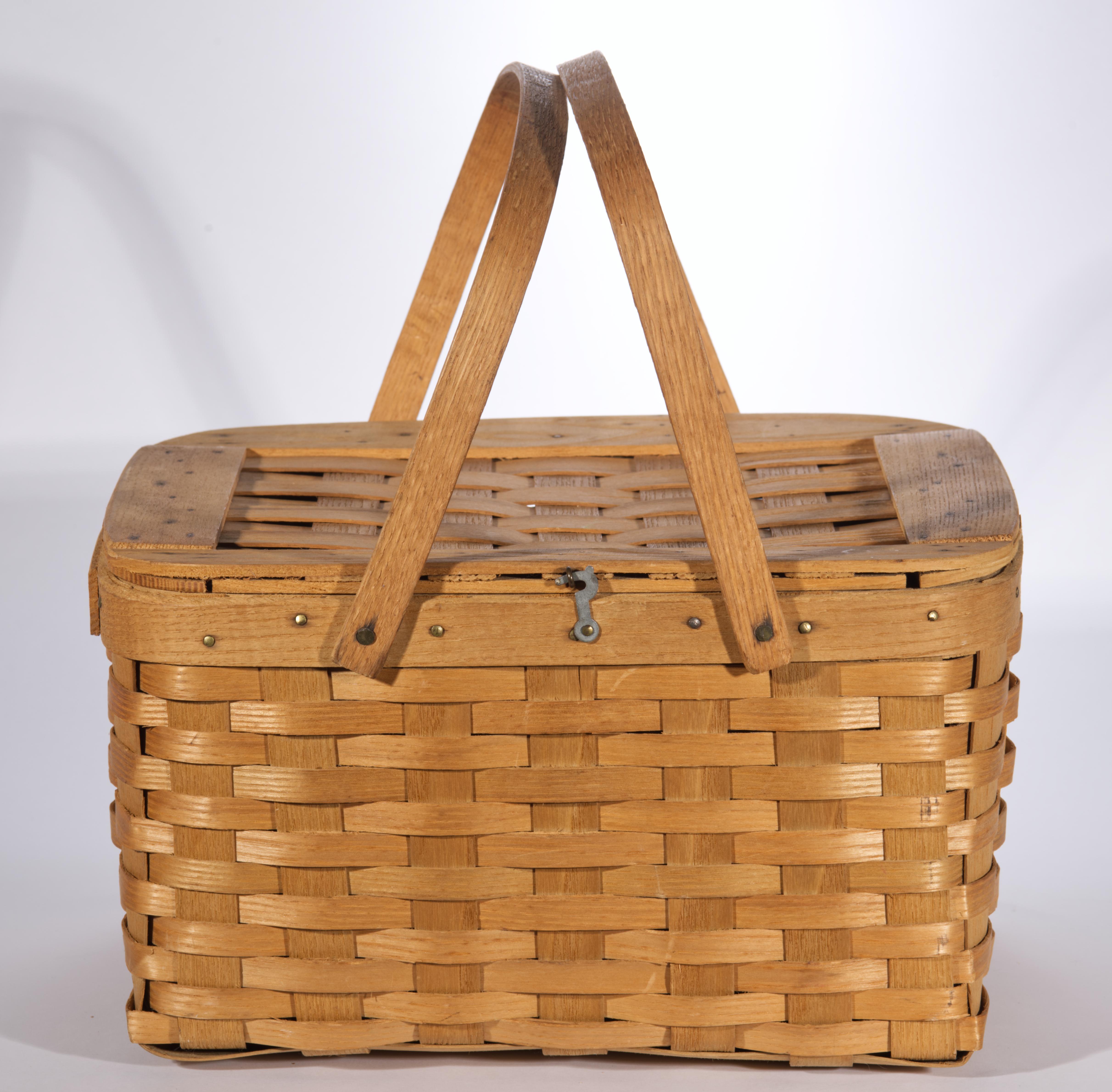 Antique or vintage woven pie, picnic, or market basket features a traditional rectangular shape with reinforced rim, hinged lid, wooden shelf insert, and twin solid wood handles. The rim is formed by carved bent ash splints, and the lid is