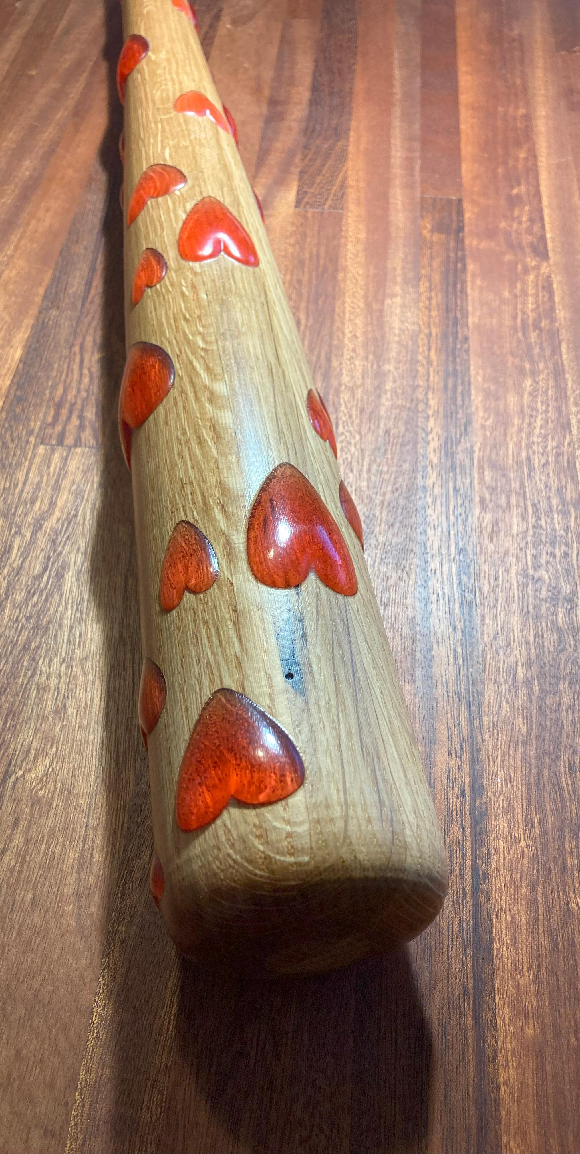 This collectable baseball bat is made from solid oak with red epoxy hearts to express love for an amazing American sport. This American made sport collectable is a top-quality unit by Fletching Interiors of California. It features red epoxy carved