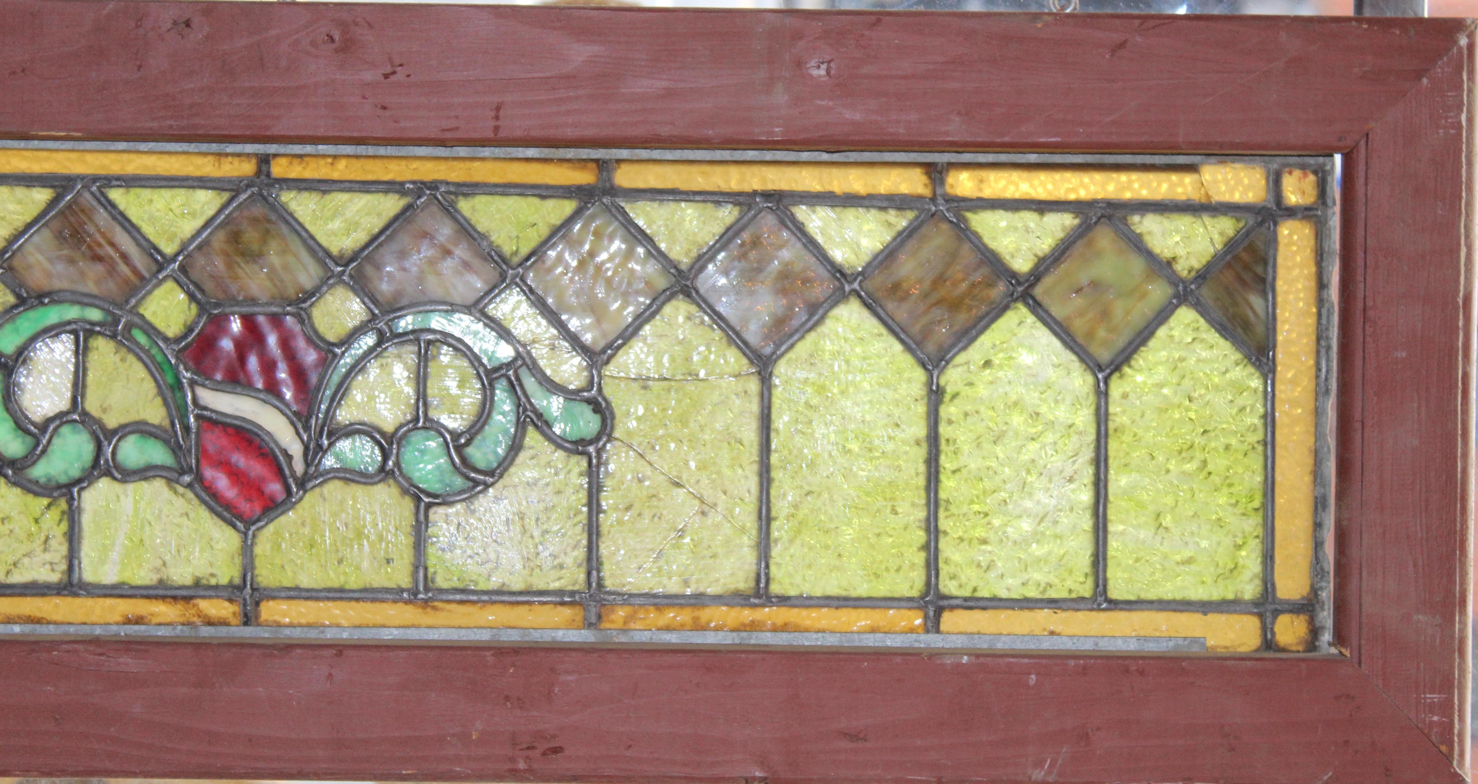 Early 20th Century transom window with stained glass designs. Green colored glass in geometric pattern with a bright red shield in the middle.
Currently housed in a wooden frame - the overall dimensions are for the stained glass and the