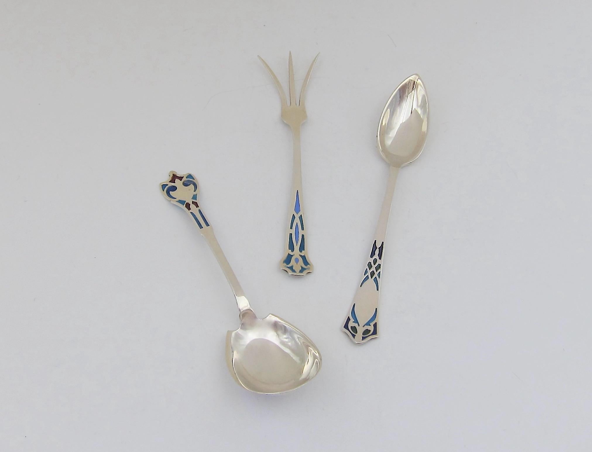 Three early 20th century American sterling silver utensils with vivid plique-à-jour enamel finials. All three specialty pieces of silver flatware are marked STERLING with New England maker's marks. The grapefruit spoon (with pointed bowl) bears the