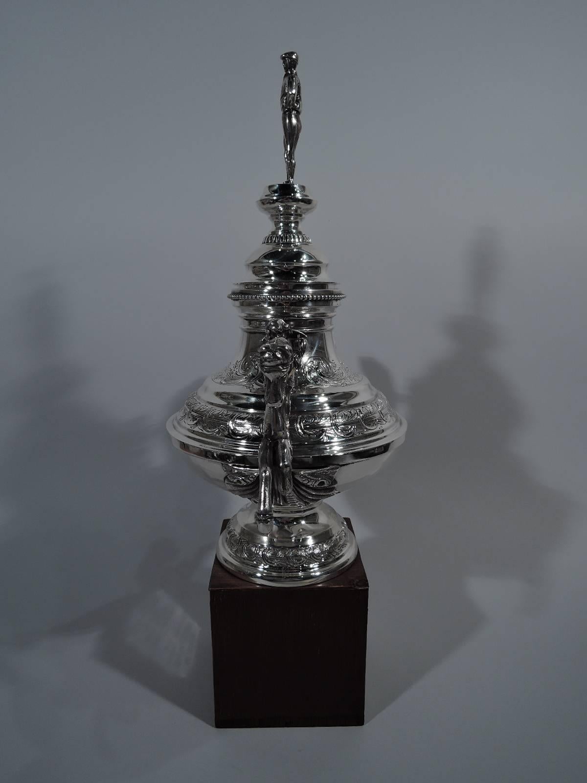 American sterling silver covered trophy. Bellied vase on domed foot. Double-domed foot. Chased leaf-and-horseshow garlands and floral and foliate-scrolled ornament. Beading and gadrooning. Mounted to sides are cast equestrian figures: A surging