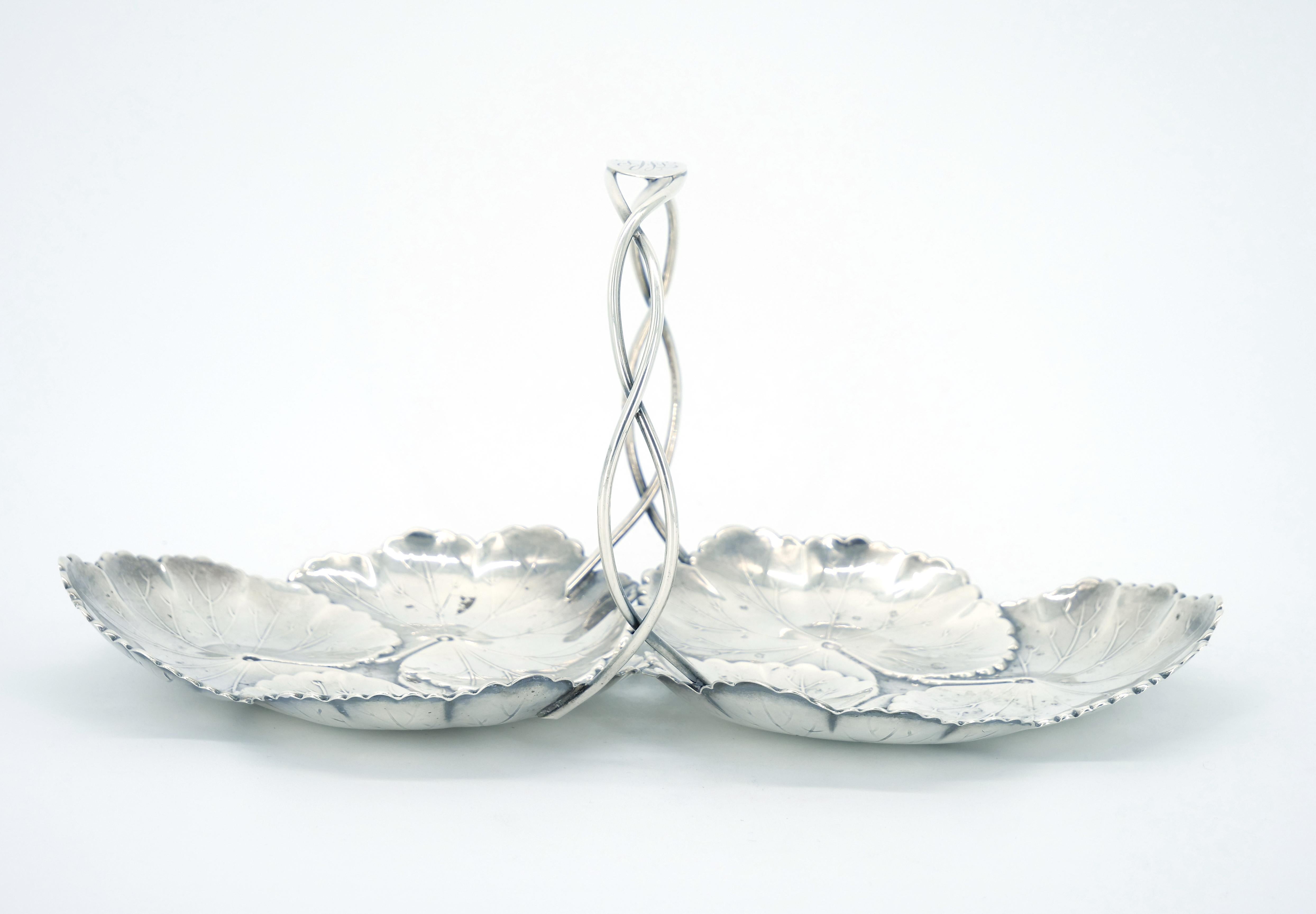 
Experience the enchanting beauty of this American sterling silver serving dish by Reed and Barton, adorned with a captivating water lily pad motif and a gracefully curved holding handle. Immerse yourself in the elegance and artistry of this