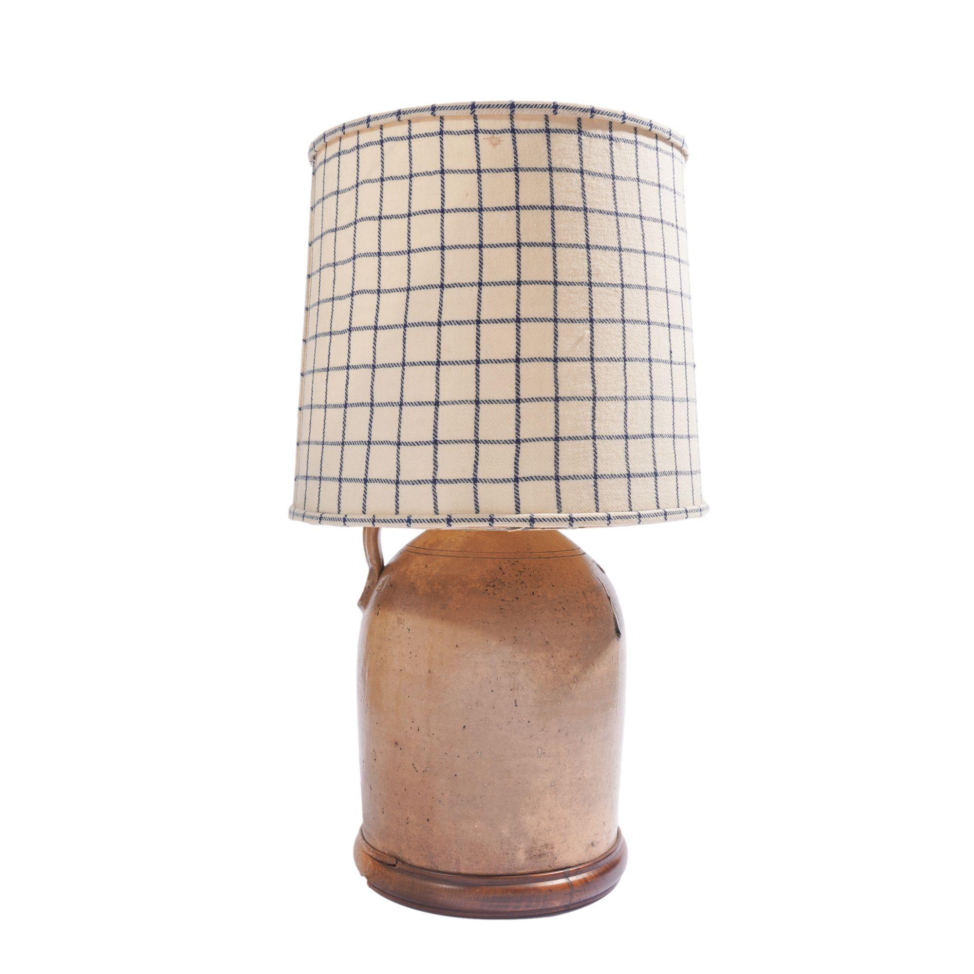 American stoneware jug with applied finger ring handle, electrified for use as a lamp. The shoulder of the jug is decorated in a cobalt glazed flower. The lamp has been mounted on a custom turned wood base and fitted with a custom shade of antique