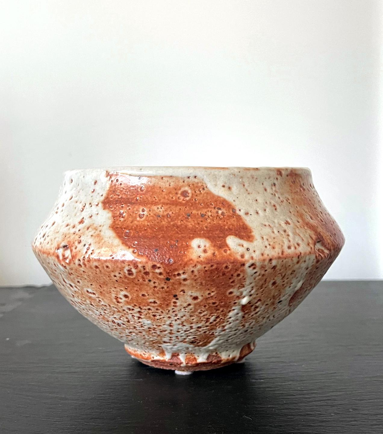 A studio made ceramic tea bowl (Chawan) with a slightly irregular form and exceptional surface glaze by American potter Warren Mackenzie (1924-2018). Reminiscent of a monk's begging bowl, the stoneware was covered in an orange and white Shino ware