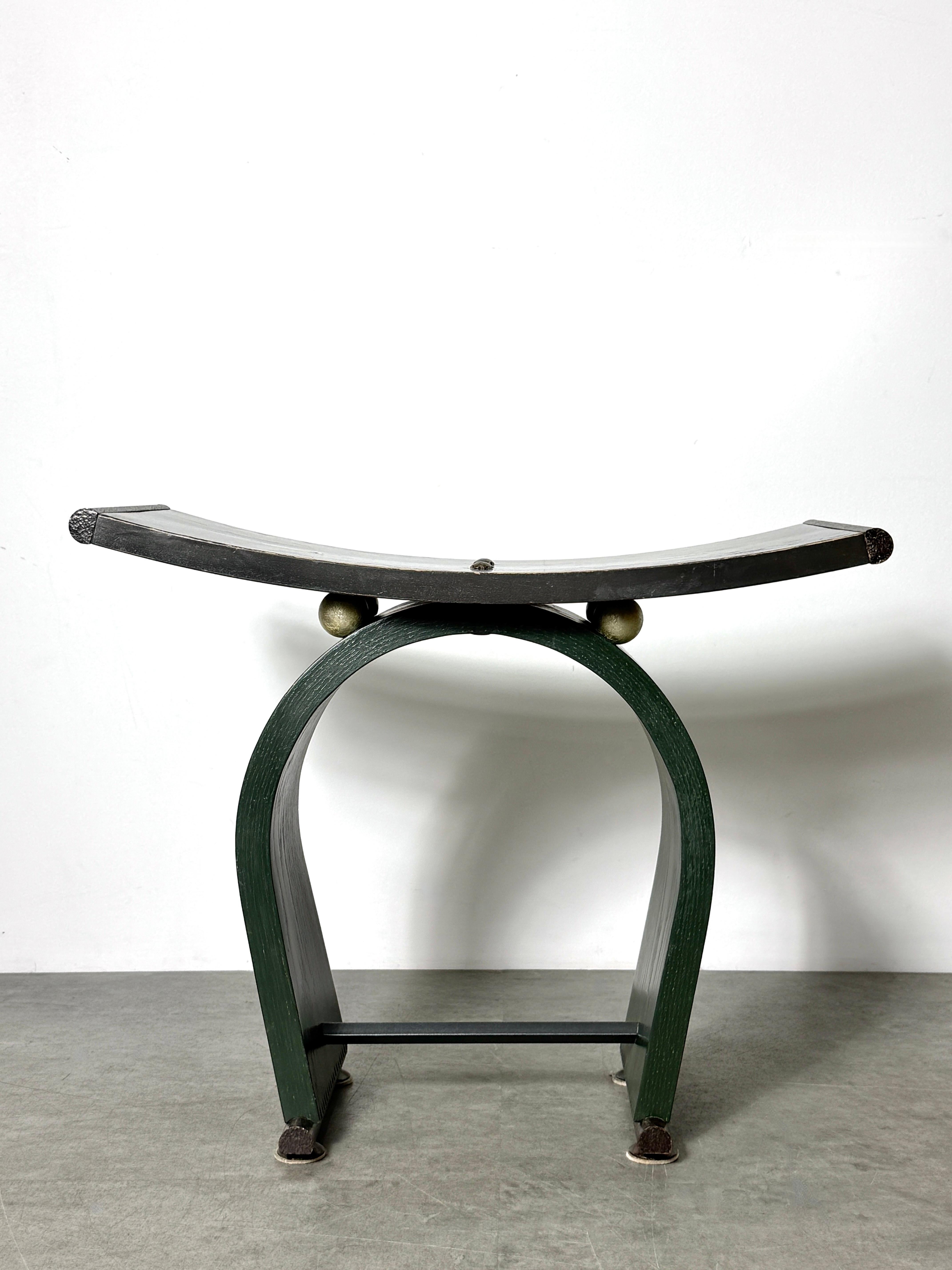 Un taburete distintivo del artista de estudio estadounidense David N. Ebner
EEUU 1992

Asiento de silla curvado sobre una base arqueada de roble, pintado a mano en verde oscuro con bordes de dientes de sierra tallados
El embellecedor de metal