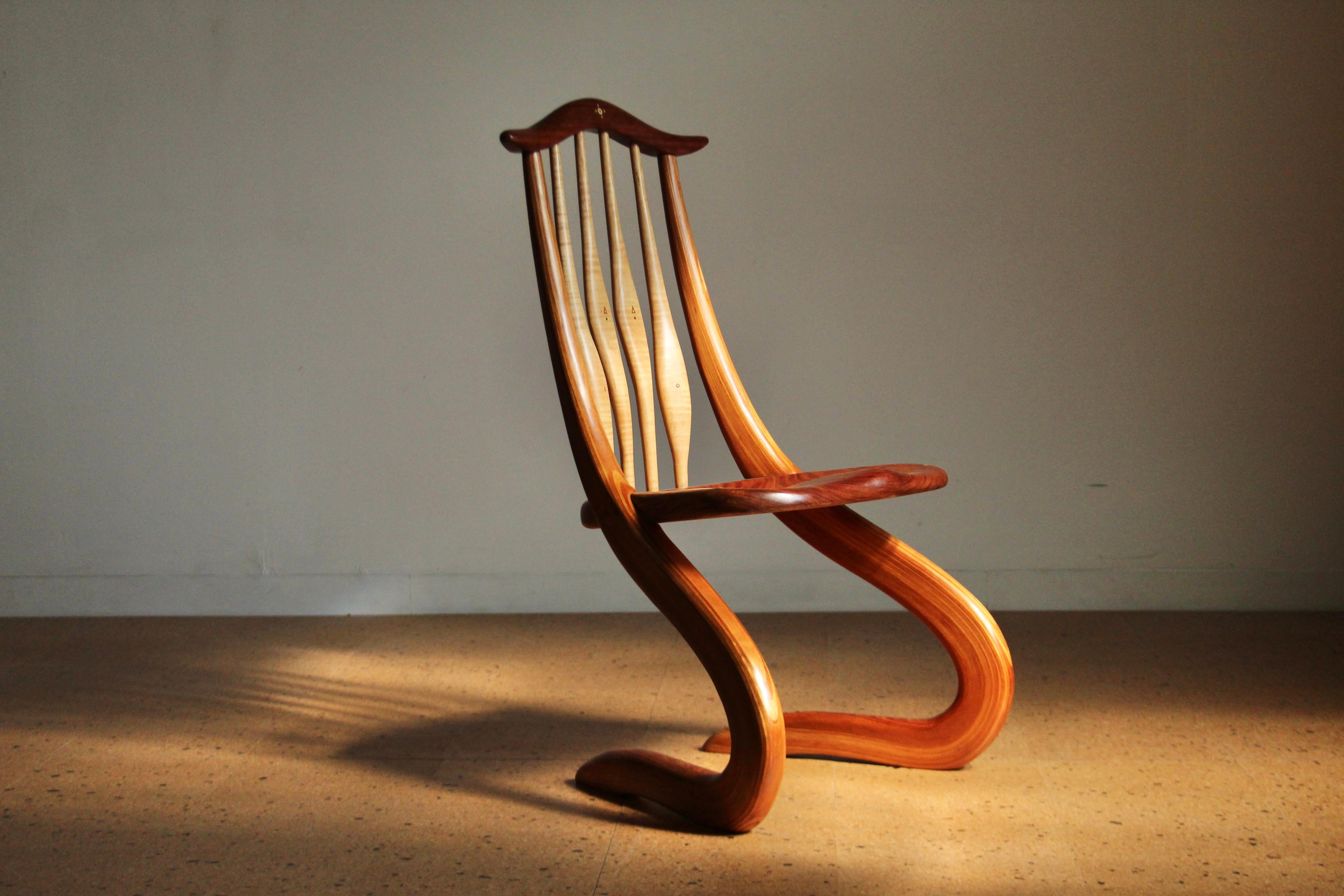 Una sedia mozzafiato scolpita e intarsiata realizzata dall'artista americano Steven Spiro. Questo pezzo unico presenta una forma organica, sinuosa e a sbalzo in legno scolpito e curvato. La seduta e lo schienale sono caratterizzati da stravaganti