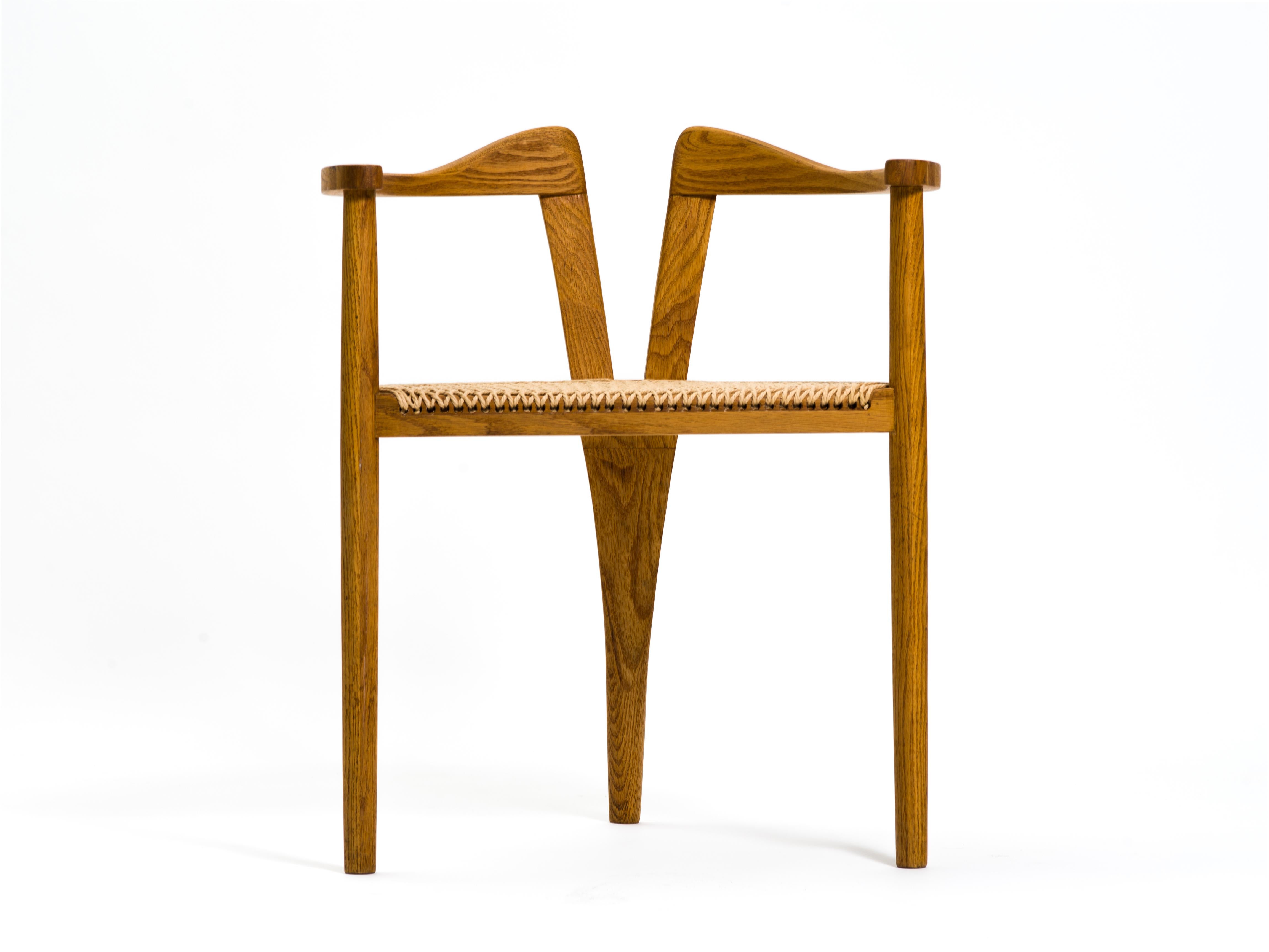 Une remarquable chaise d'atelier à trois pieds, exécutée en chêne massif et finie avec un siège en corde de papier tissé à la main aux motifs magnifiques. Les accoudoirs ondulés sont soutenus par des pieds goujons de style danois, celui de l'arrière