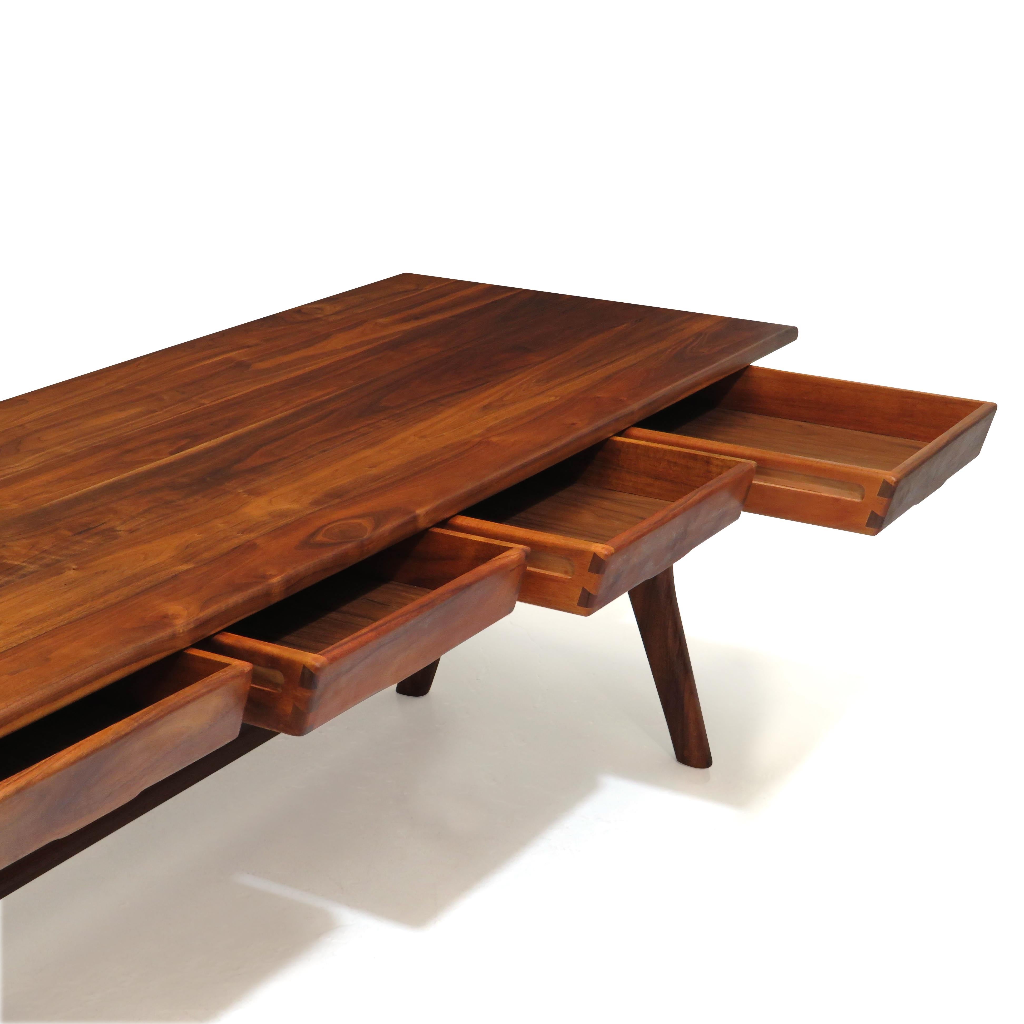 California studio desk by Berkeley craftsman Jim Sweeney. The desk is crafted of a solid Walnut and Koa, features four drawers with exposed joinery on sides, raised on the angled trestle legs with cross stretcher.