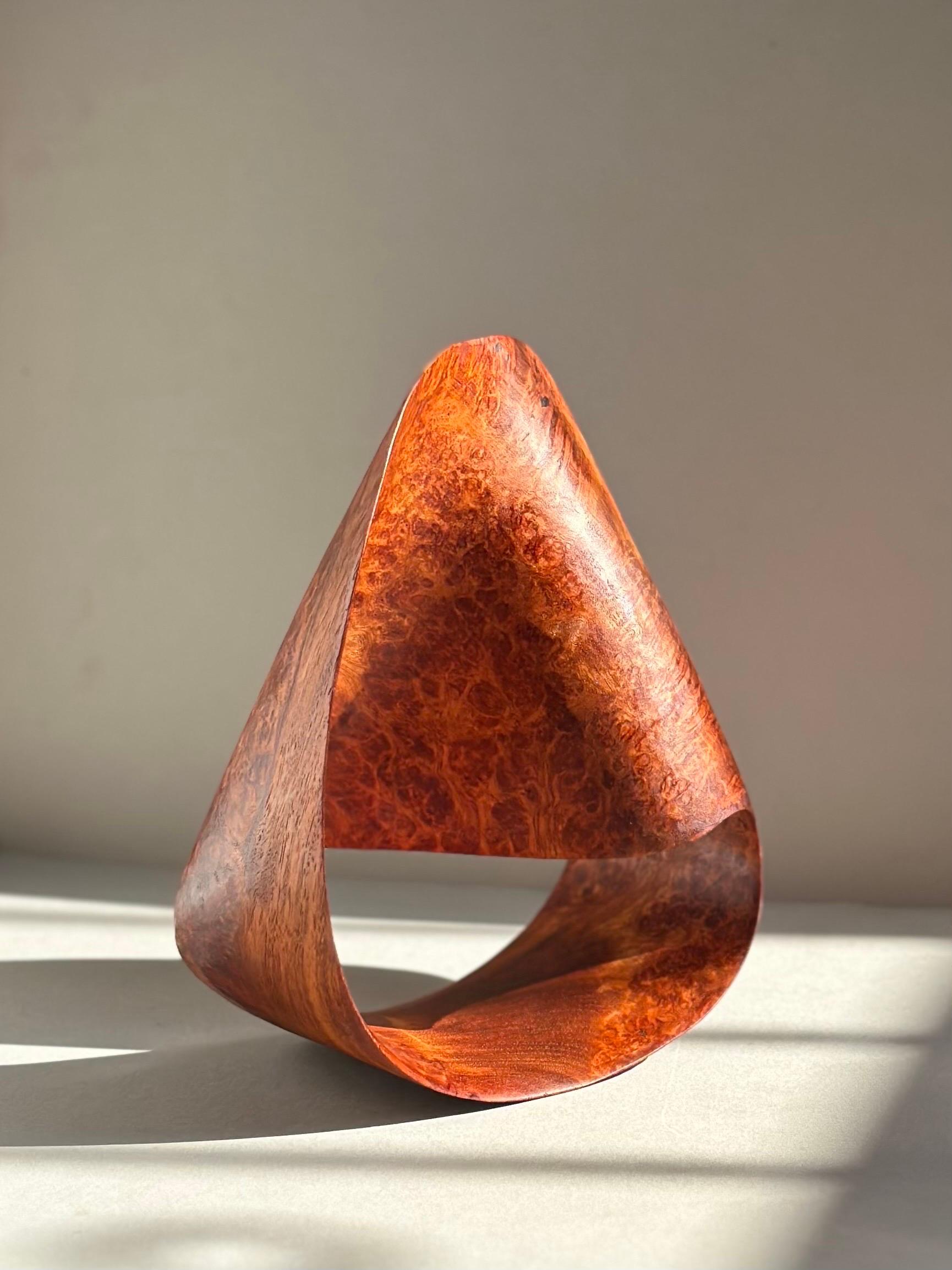 A Mobius Strip sculpture expertly crafted in steam bent maple burl with beautiful figure and an even patina. The Mobius strip is an alluring object discovered in the mid 19th century whose properties serve as an apt representation of the human