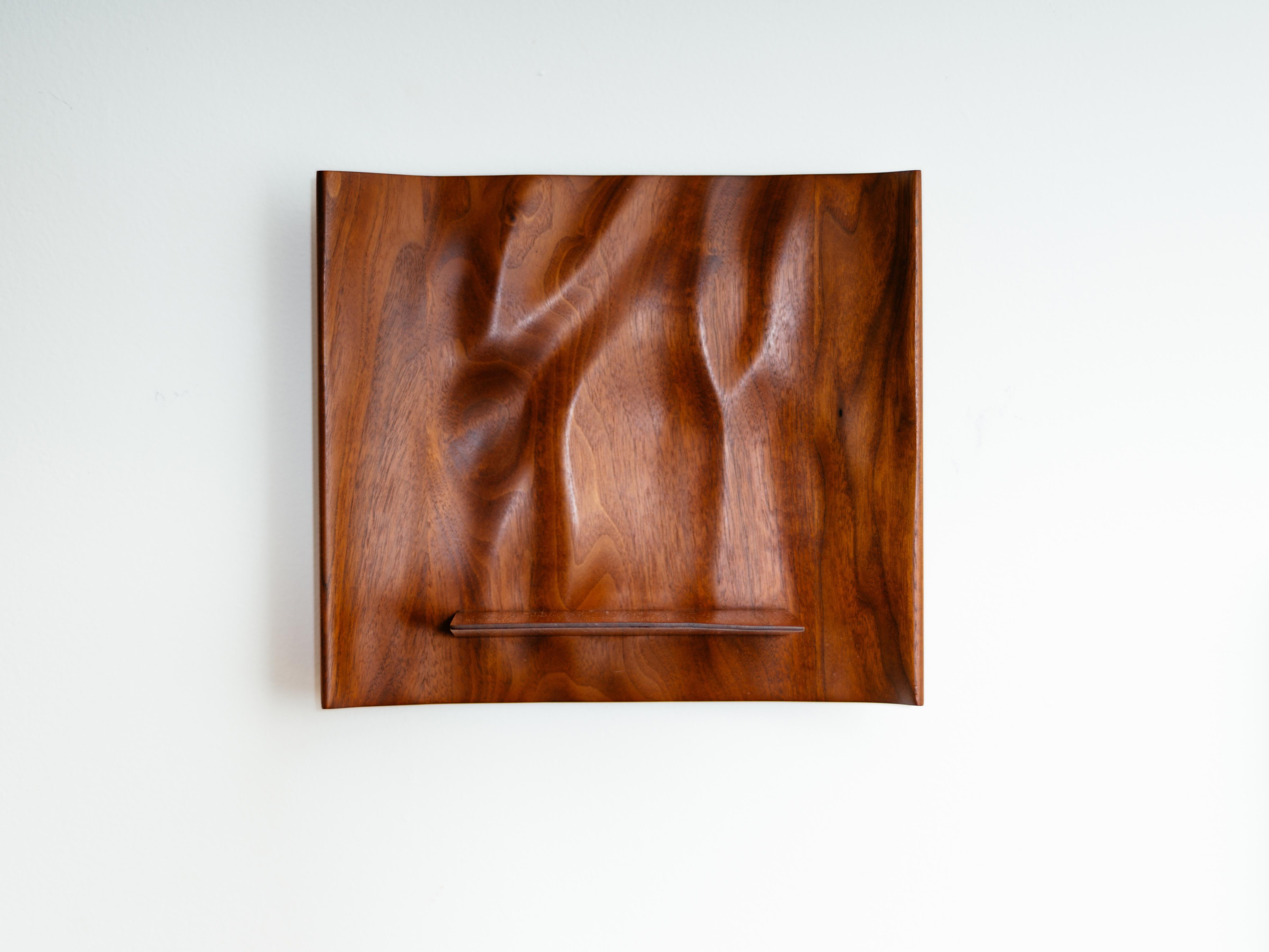 A stunning, petite Studio wall shelf with a sensually carved, concave back and a wedge-shaped ledge by American craftsman, Roger Sloan. A work of art on its own, this piece will perfectly highlight your favorite object. Signed to the reverse. Circa