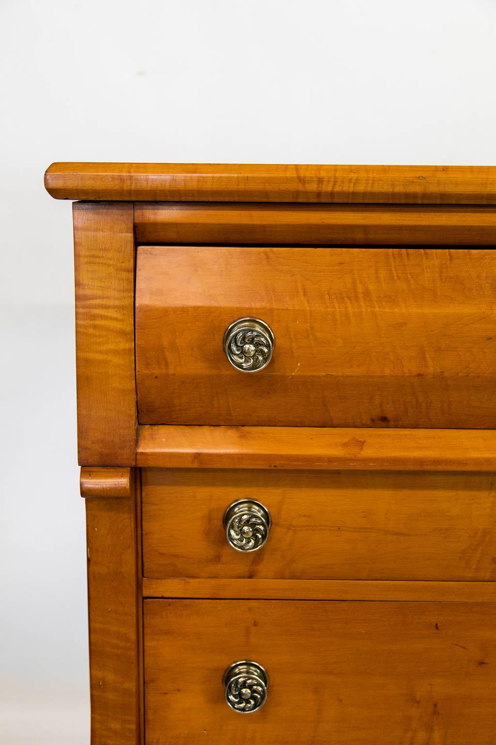 The locks on this chest are original. The brass hardware is later. The front styles have a scrolled shape and terminate in turned legs. The top drawer has a tri-faceted shape as does the top molding.