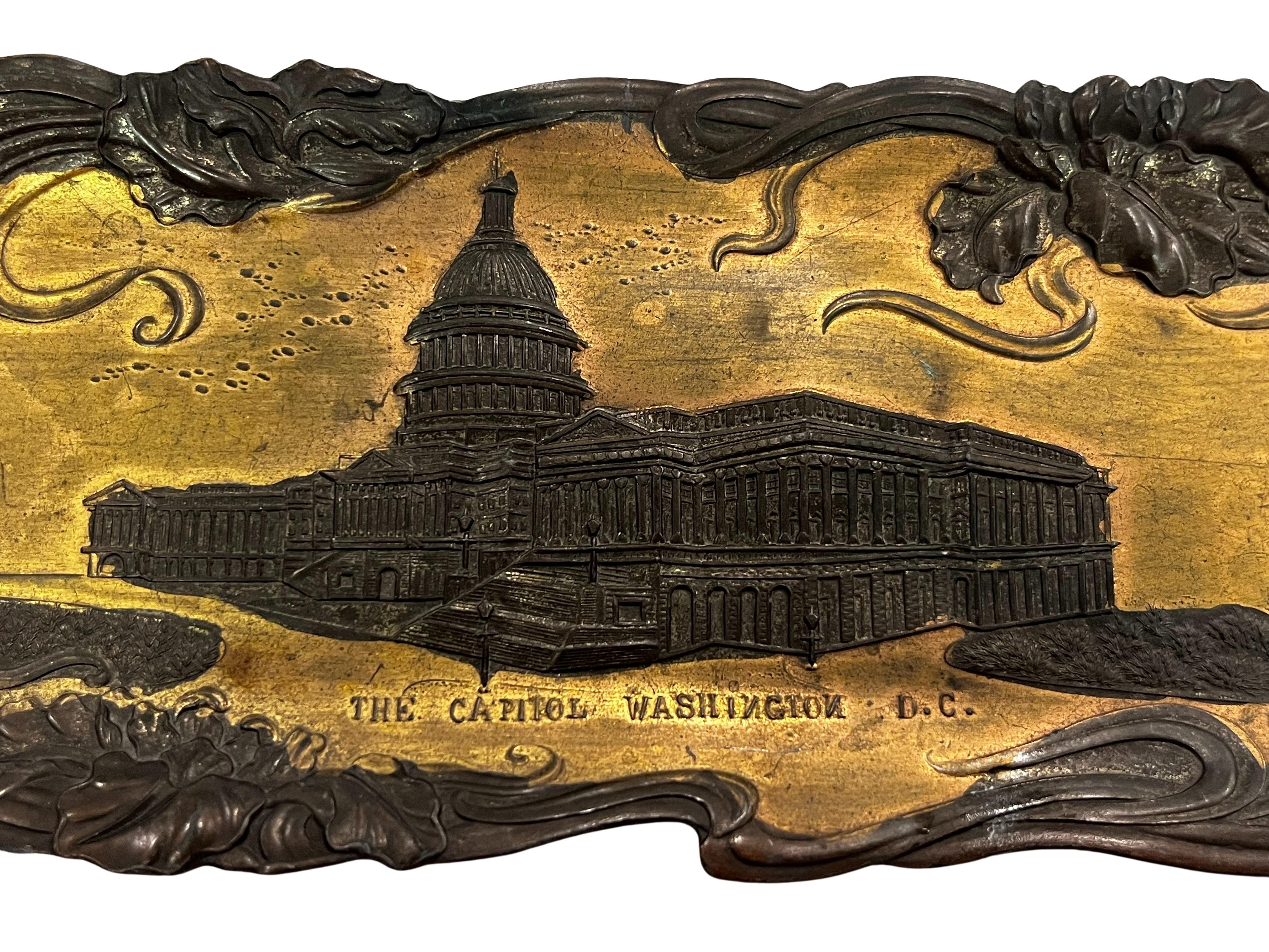 A piece of American history: a metal tray with the Capitol in Washington D.C. from around 1900, made in New York.

This object was made by Bosselman & Co. in New York around 1900. It depicts a golden background surrounded by floral tendrils and
