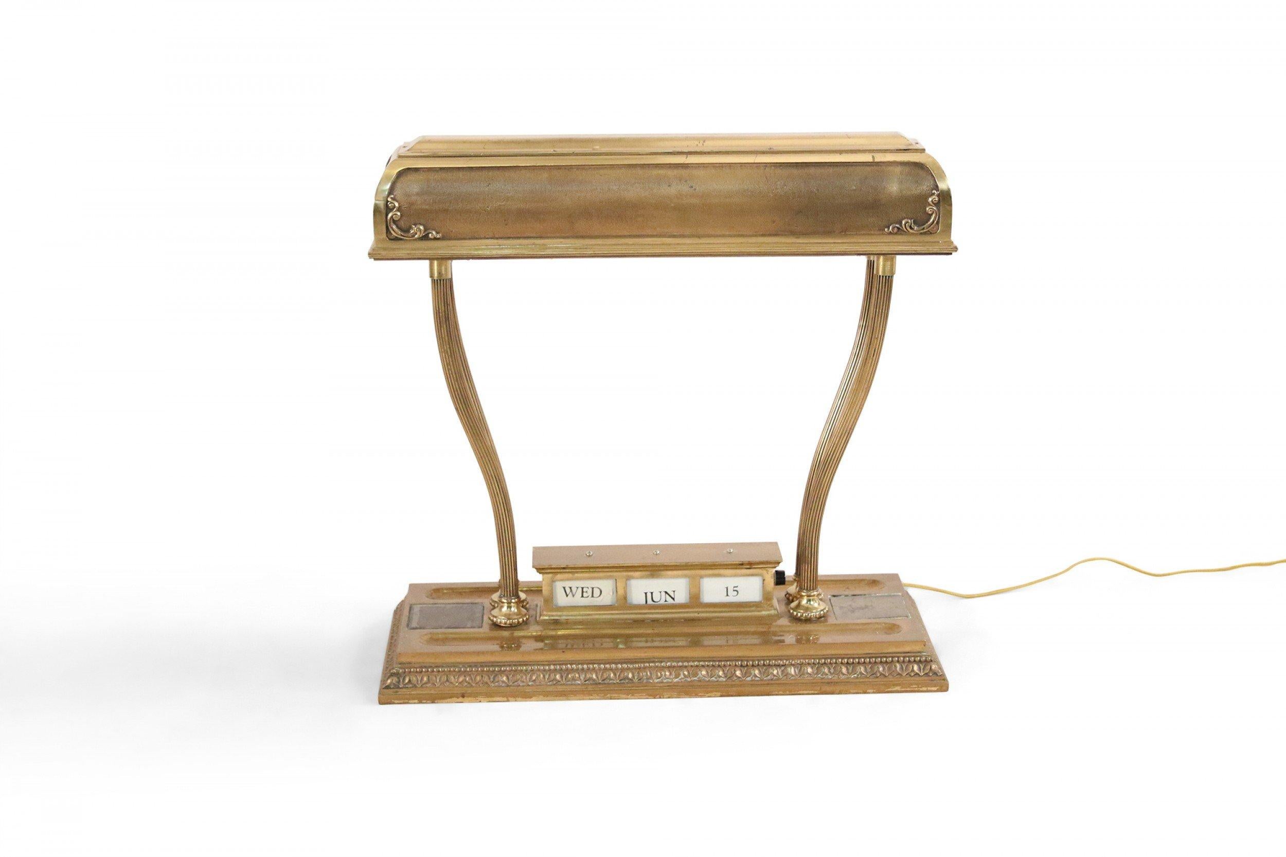 American Victorian large brass rectangular desk lamp with adjustable calendar display on a rectangular base supporting a large brass shade.