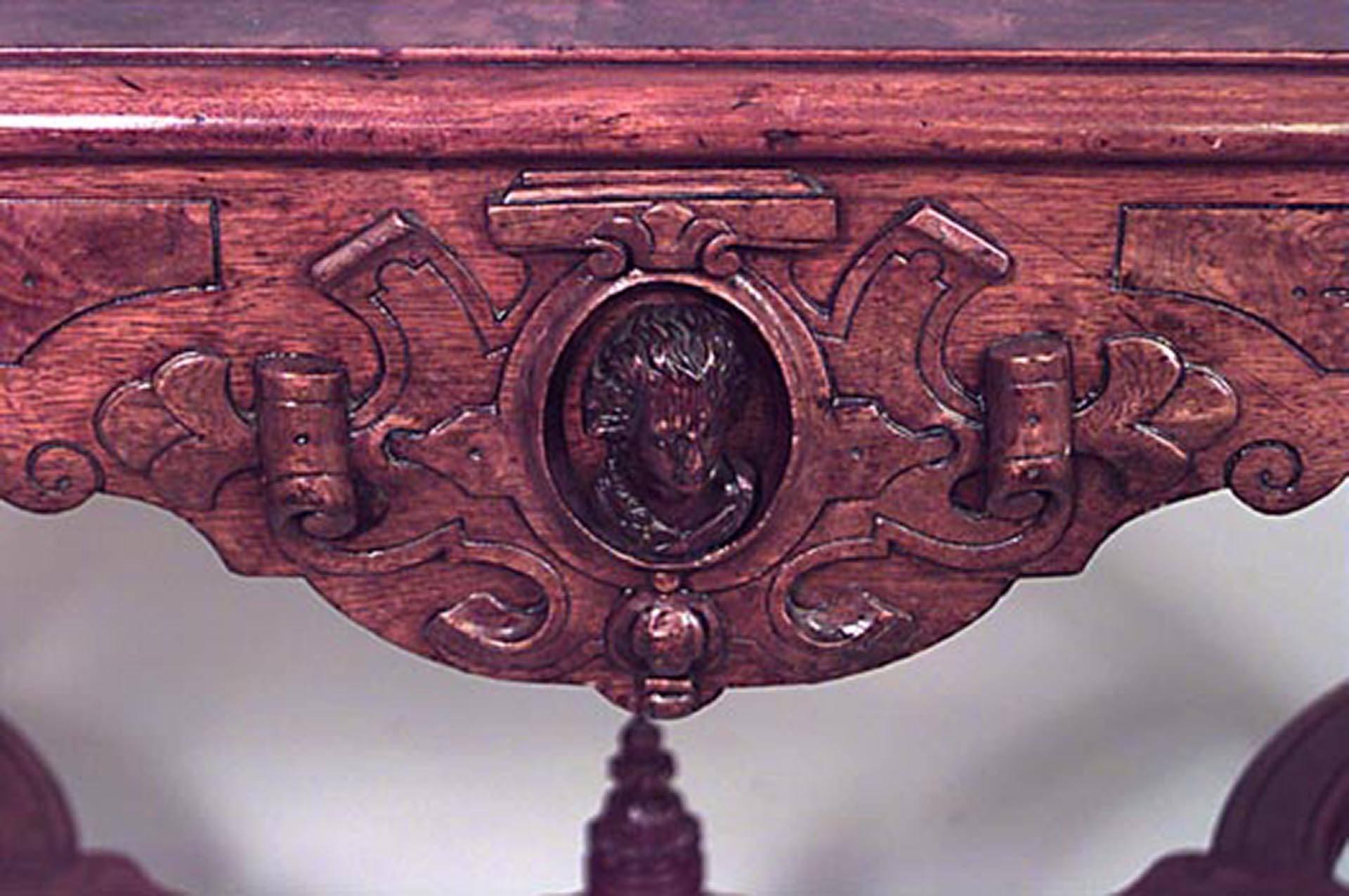 American Victorian burl walnut center table with carved heads of leading writers and statesmen with center finial on the stretcher and brown leather top.
