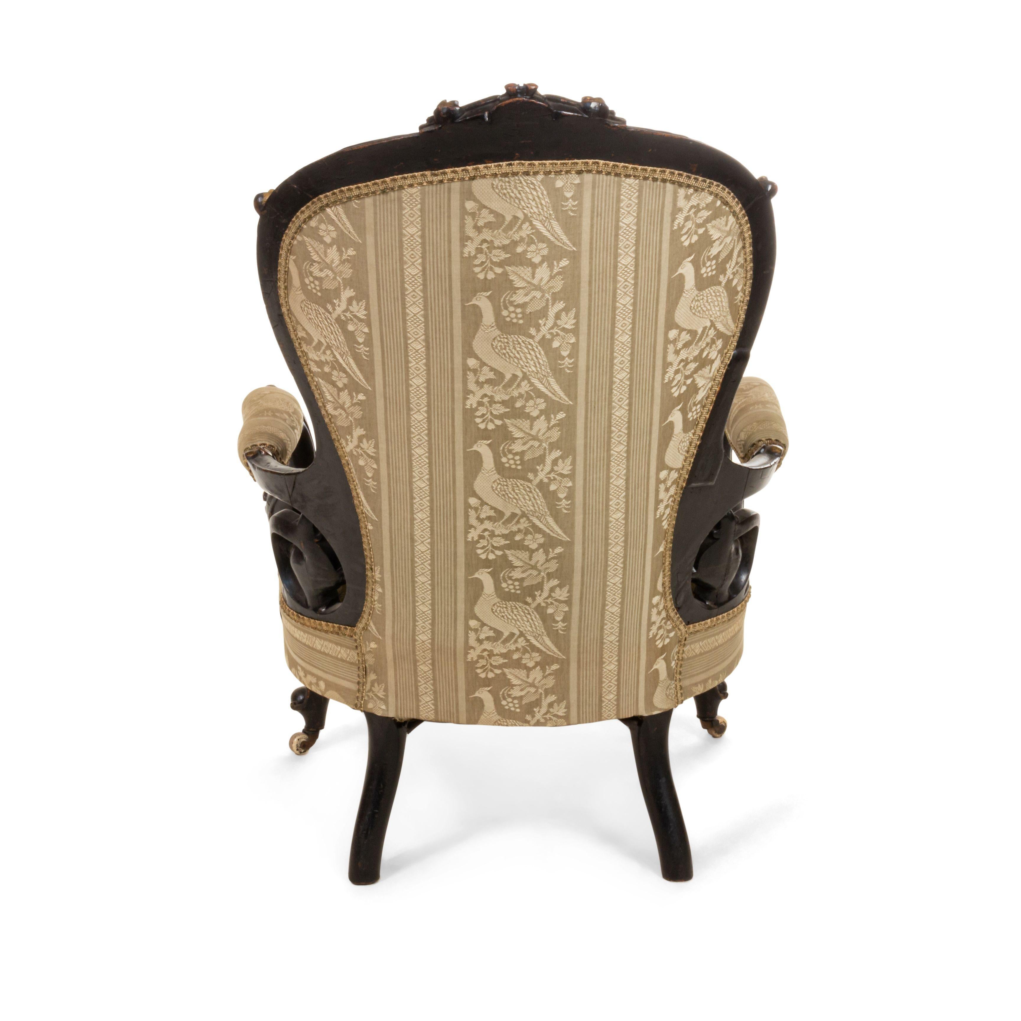 American Victorian ebonized and gold trimmed arm chair with carved floral motifs and green stripe upholstery.
      