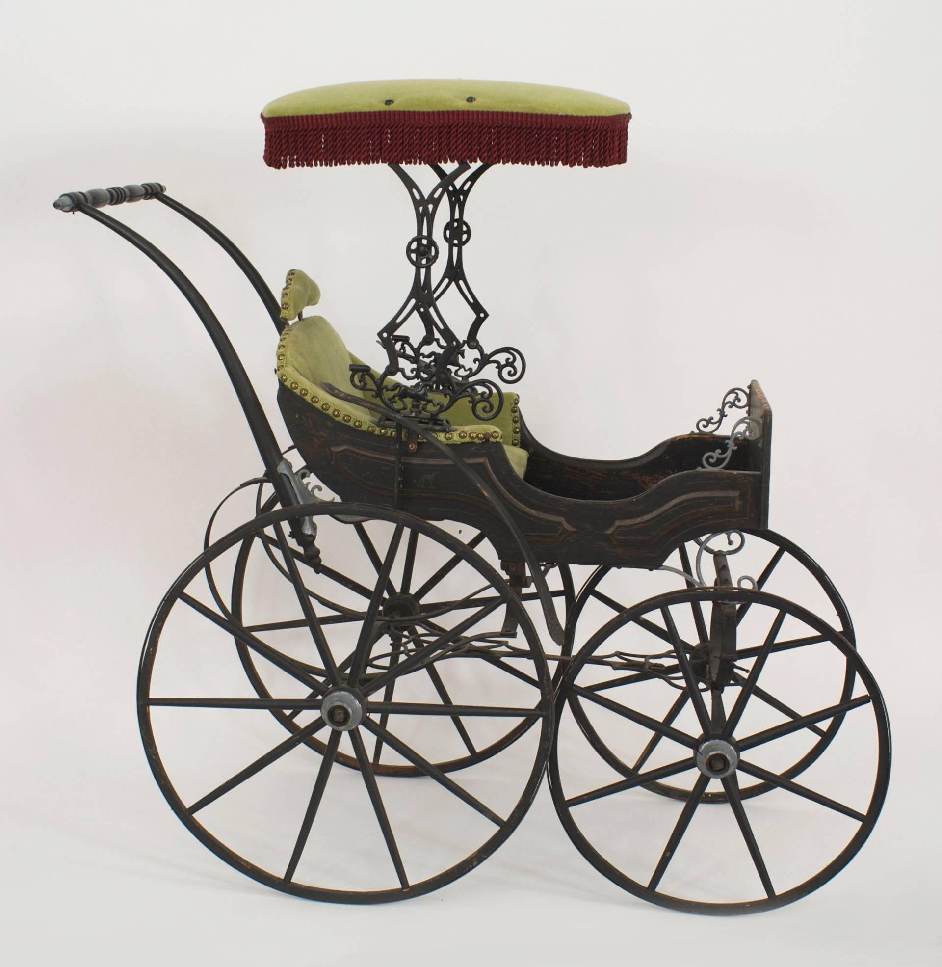 American Victorian iron and wood fancy baby carriage with green velvet upholstery and canopy.
