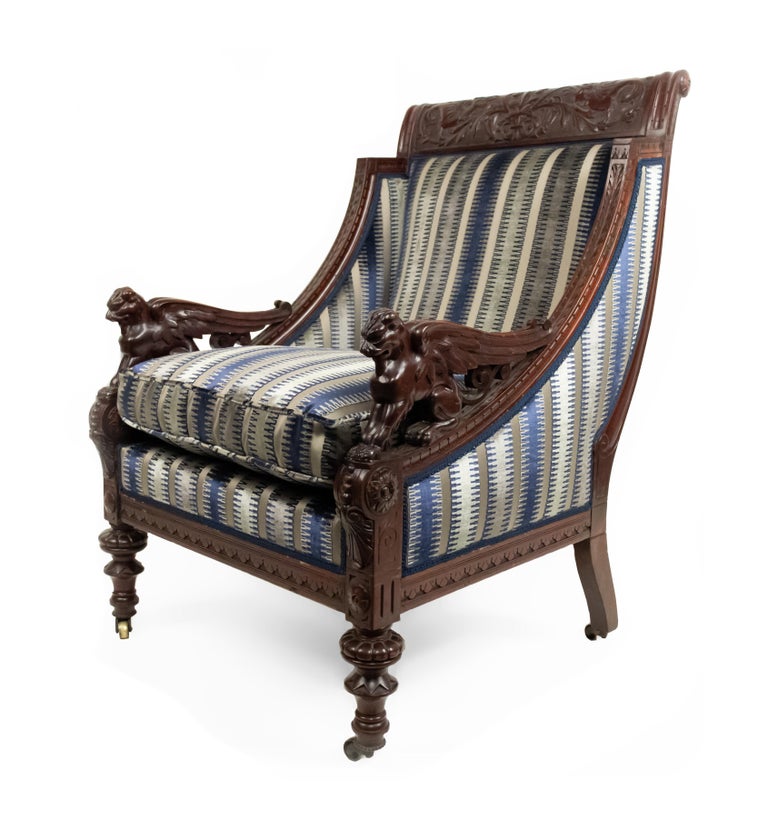American Victorian mahogany arm chair with winged griffin arms and blue and grey striped upholstery.
