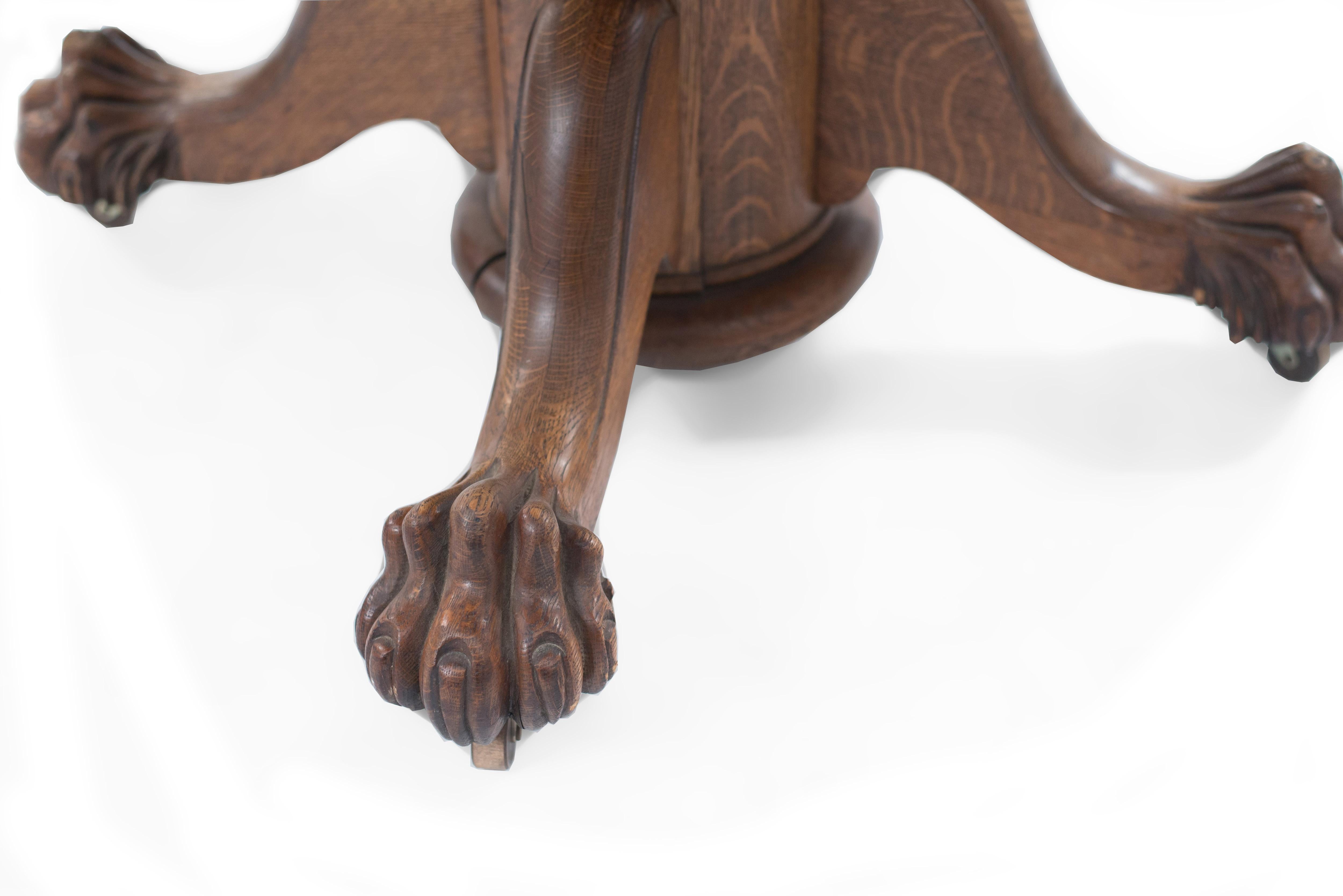 American Victorian (19/20th Century) golden oak round dining table with carved claw feet and 1 leaf.
  