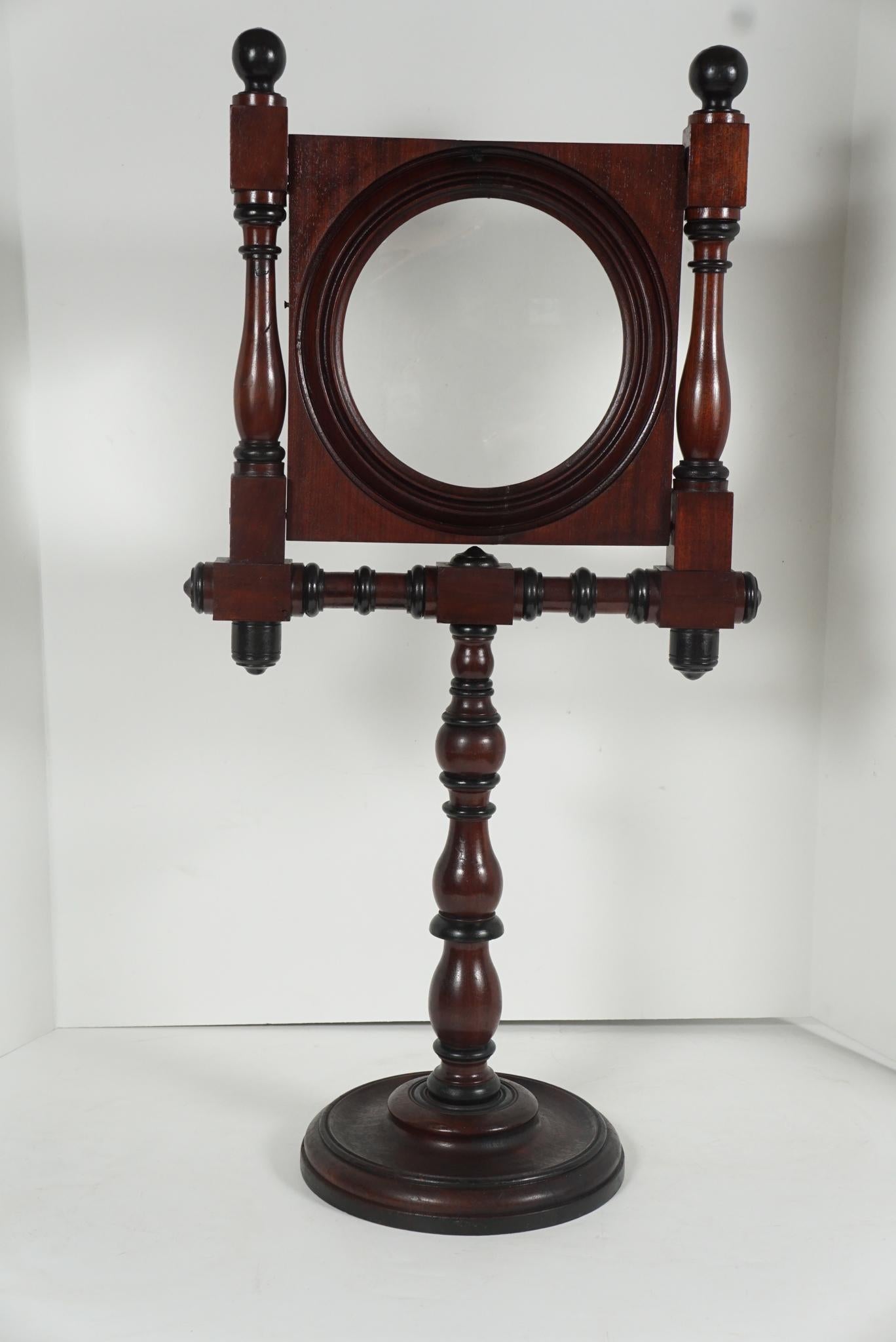 Cette grande loupe victorienne américaine est encastrée dans un cadre en noyer sculpté et tourné. Elle est réglable en hauteur à l'aide d'un dispositif à vis en bois. Fabriqué vers 1880, le bois est richement coloré et présente sa finition