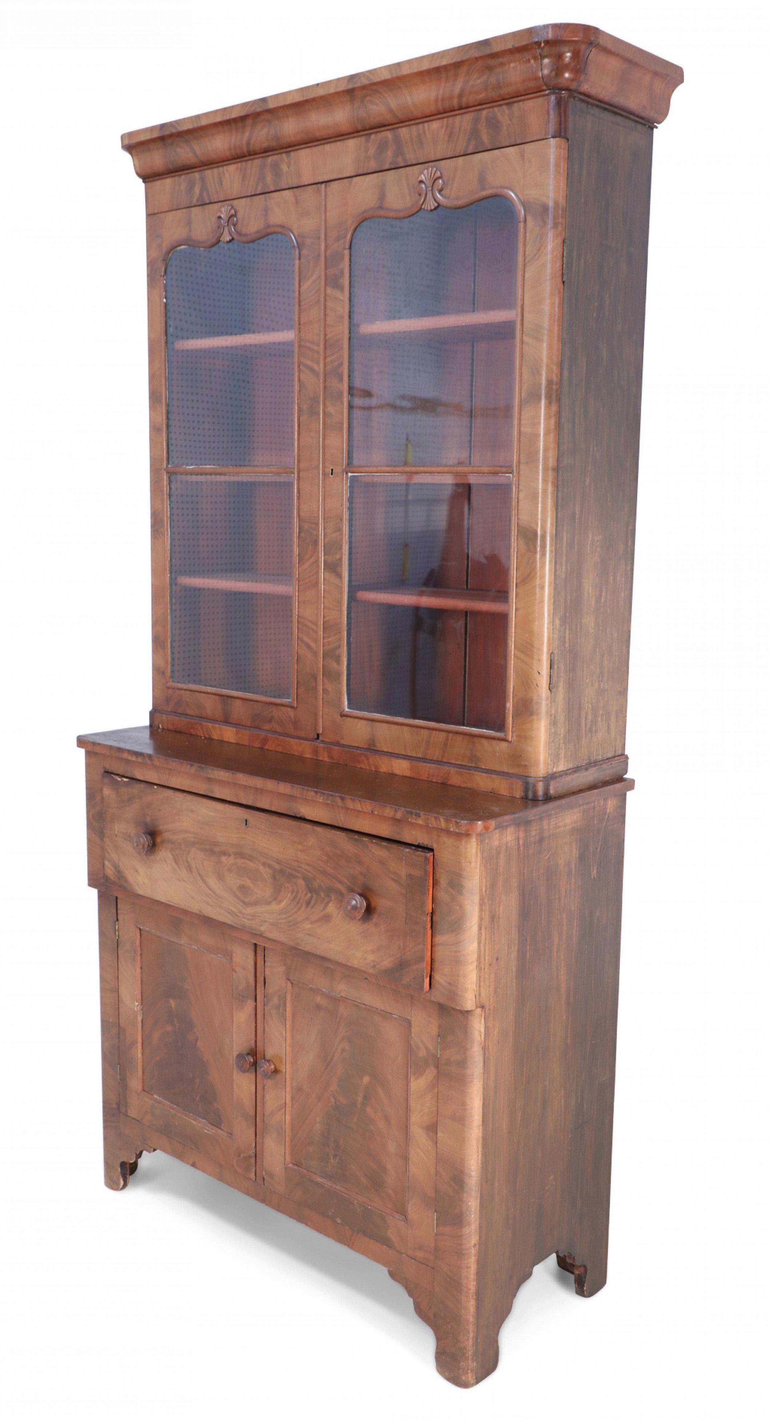 American Victorian two-piece walnut secretary cabinet with a base having a drawer whose front folds down to create a desktop with interior drawers and green felt over two doors with a back-set top section with two glass front doors and shelves.
 