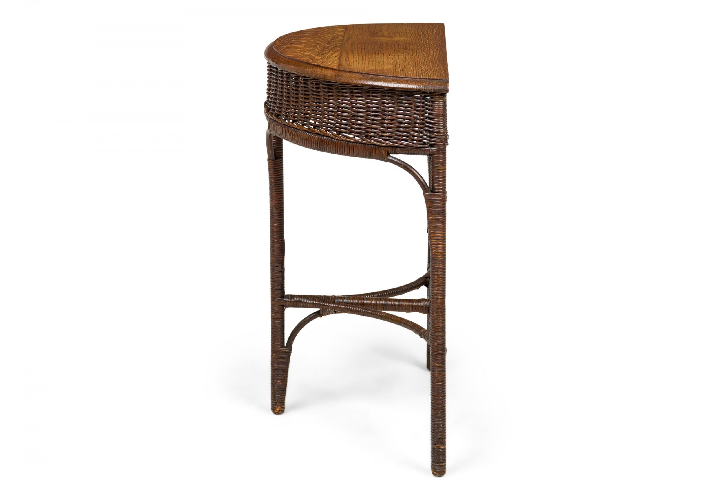American Victorian Wicker and oak topped demilune side table with beveled top edge and wicker apron, resting on 3 wicker-wrapped legs, with curved wood supports and a T-shaped stretcher base.