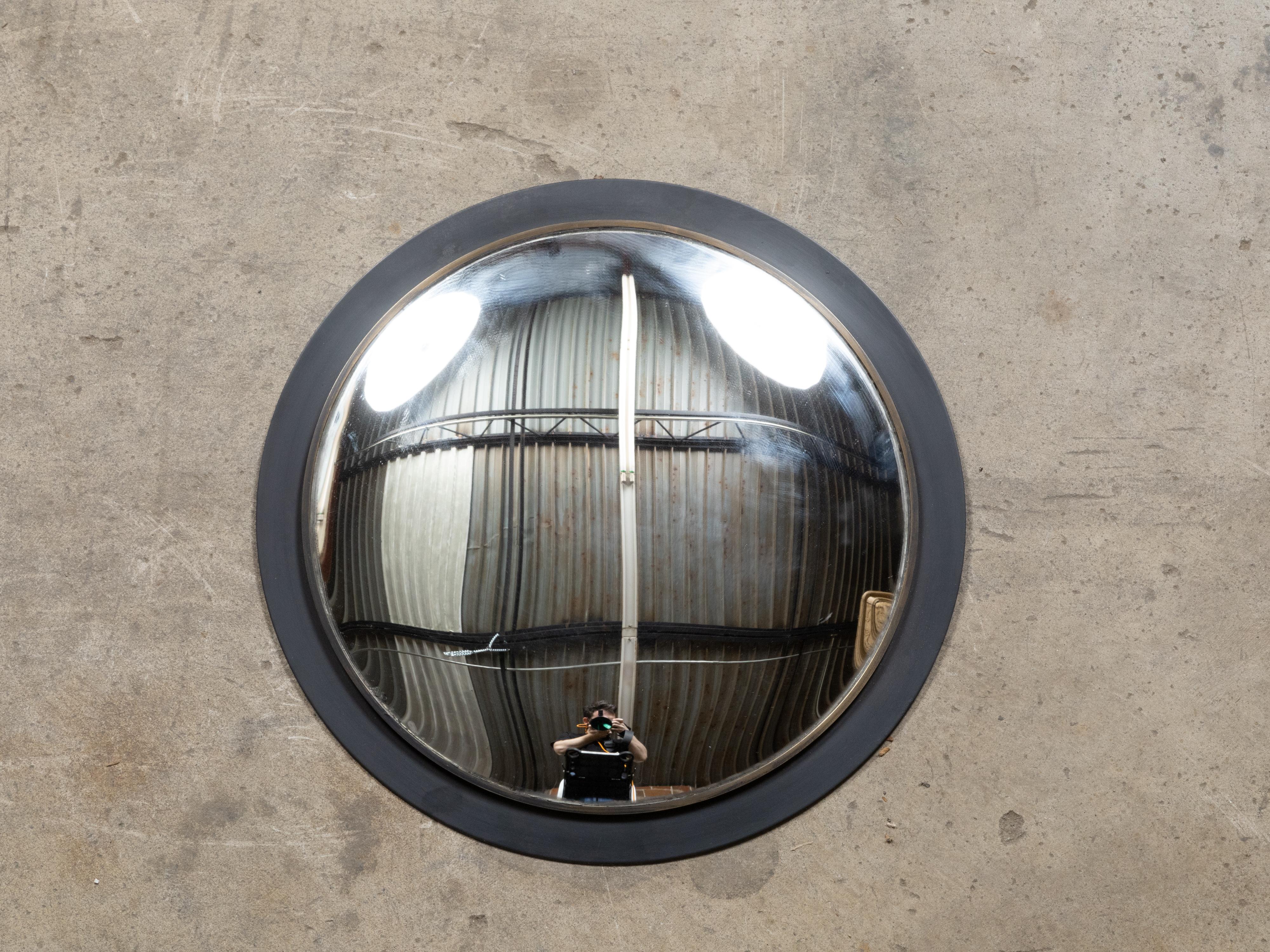 Miroir convexe américain vintage avec cadre circulaire noir. Fabriqué aux États-Unis, ce miroir convexe vintage séduit par sa capacité distinctive à déformer et à transformer les reflets, ajoutant une touche de fantaisie et d'intrigue visuelle à