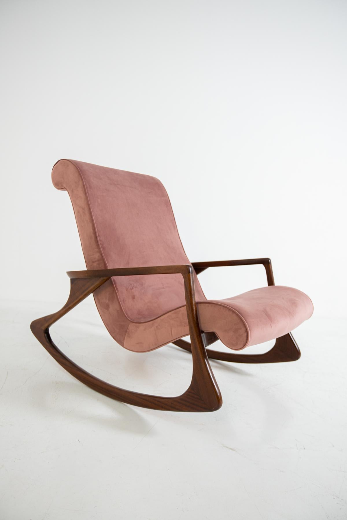 Elegant and sculptural midcentury American rocking chair. The armchair has been restored and refreshed in an elegant antique pink velvet. The seat and its back are one piece to give comfort to its guest. Its frame is made of walnut wood. Its fluid