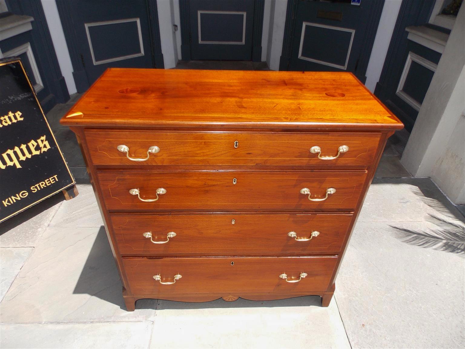 American walnut four-drawer graduated chest with a carved molded edge top , flanking burl walnut and holly inlaid ovals, corner inlaid patera's, original brasses, vine and floral holly string inlay, and terminating on a carved scalloped skirt with