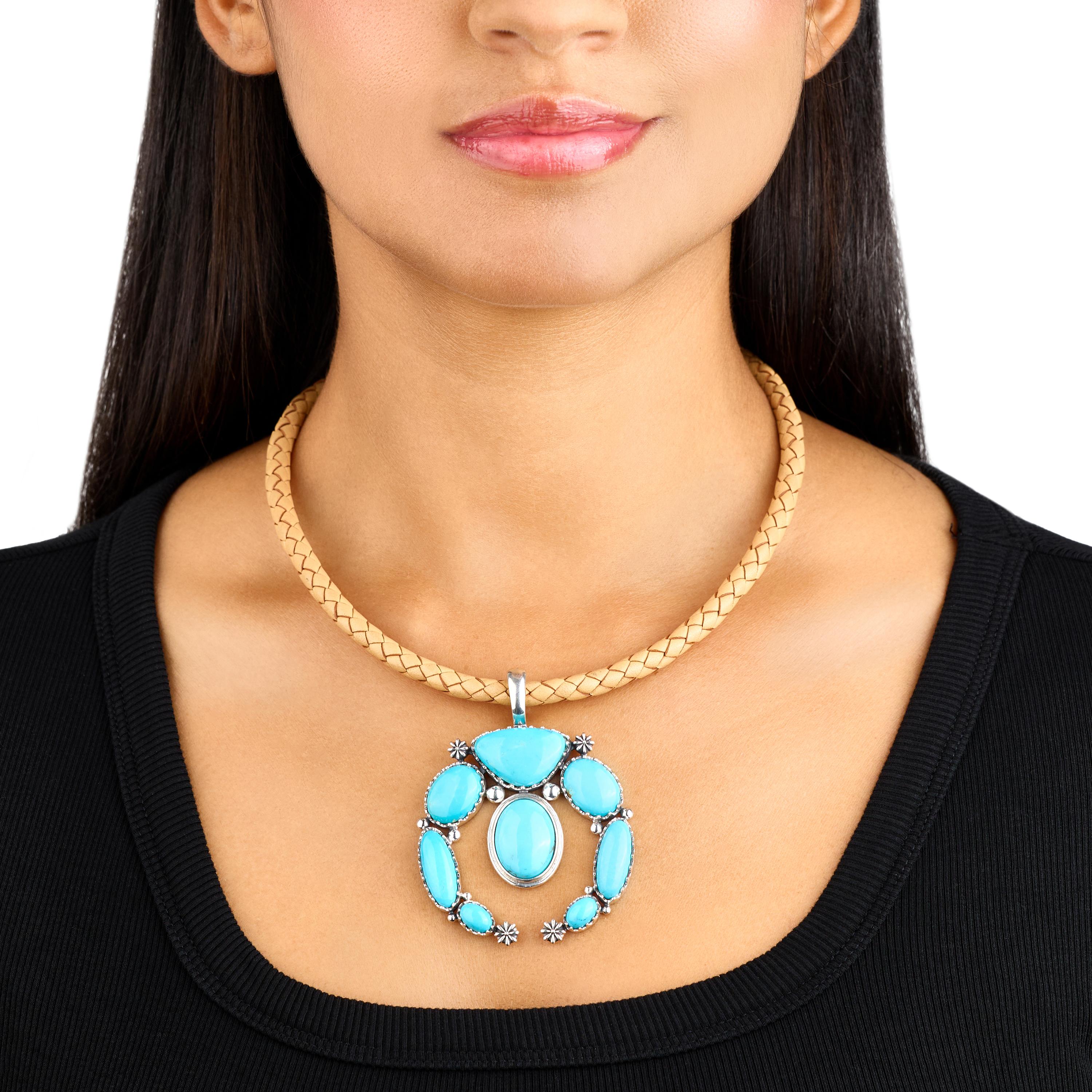 - Il ciondolo Naja presenta un bordo in argento con perline, fiori e perline in conchiglia in argento Sterling, una gemma di Turchese Kingman tagliata a triangolo e 7 gemme di Turchese Kingman tagliate a forma ovale di varie dimensioni; finitura
