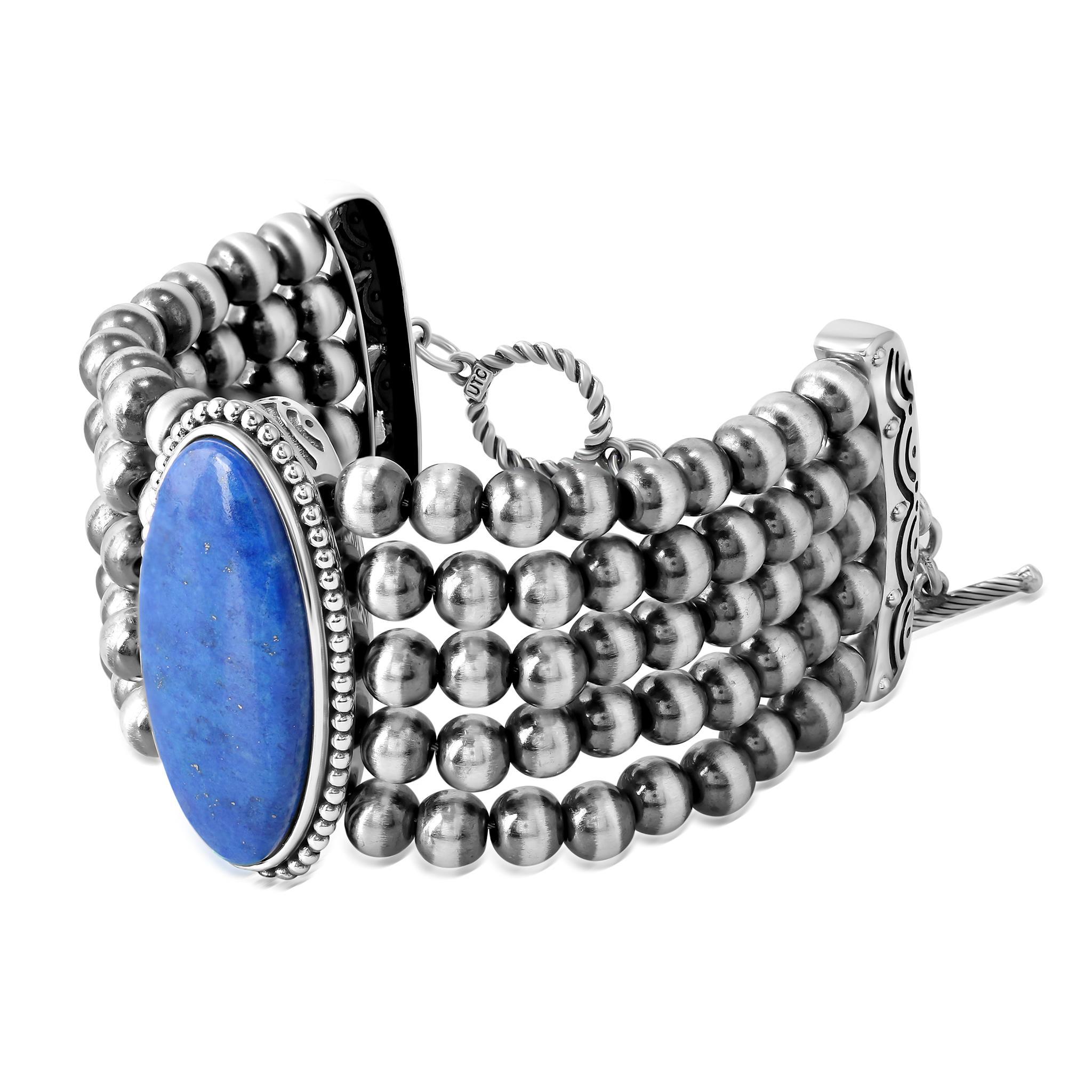 - Il bracciale presenta un'audace pietra Lapis ovale cabochon di 16 mm x 36 mm con una cornice di perline; 5 file di perline in argento Sterling ossidato e lucidato da 6 mm.
- Chiusura a gancio e barretta; la taglia piccola si adatta a polsi di