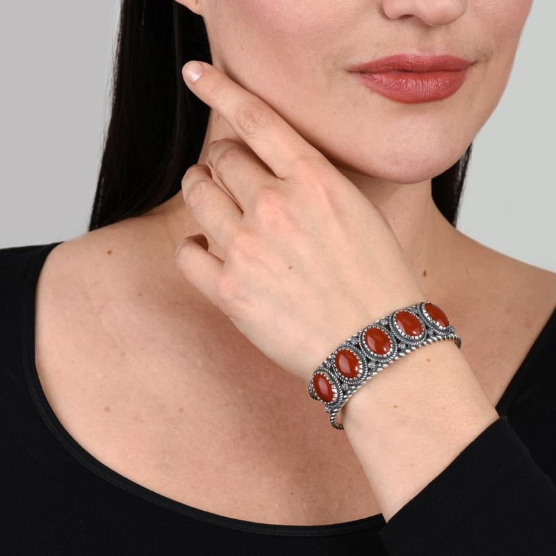 • La manchette présente cinq pierres précieuses en jaspe rouge de forme ovale de 10 x 14 mm, serties dans un chaton festonné, avec une bordure en corde, des motifs floraux en conque et des détails de la bordure en corde autour de la manchette.
•