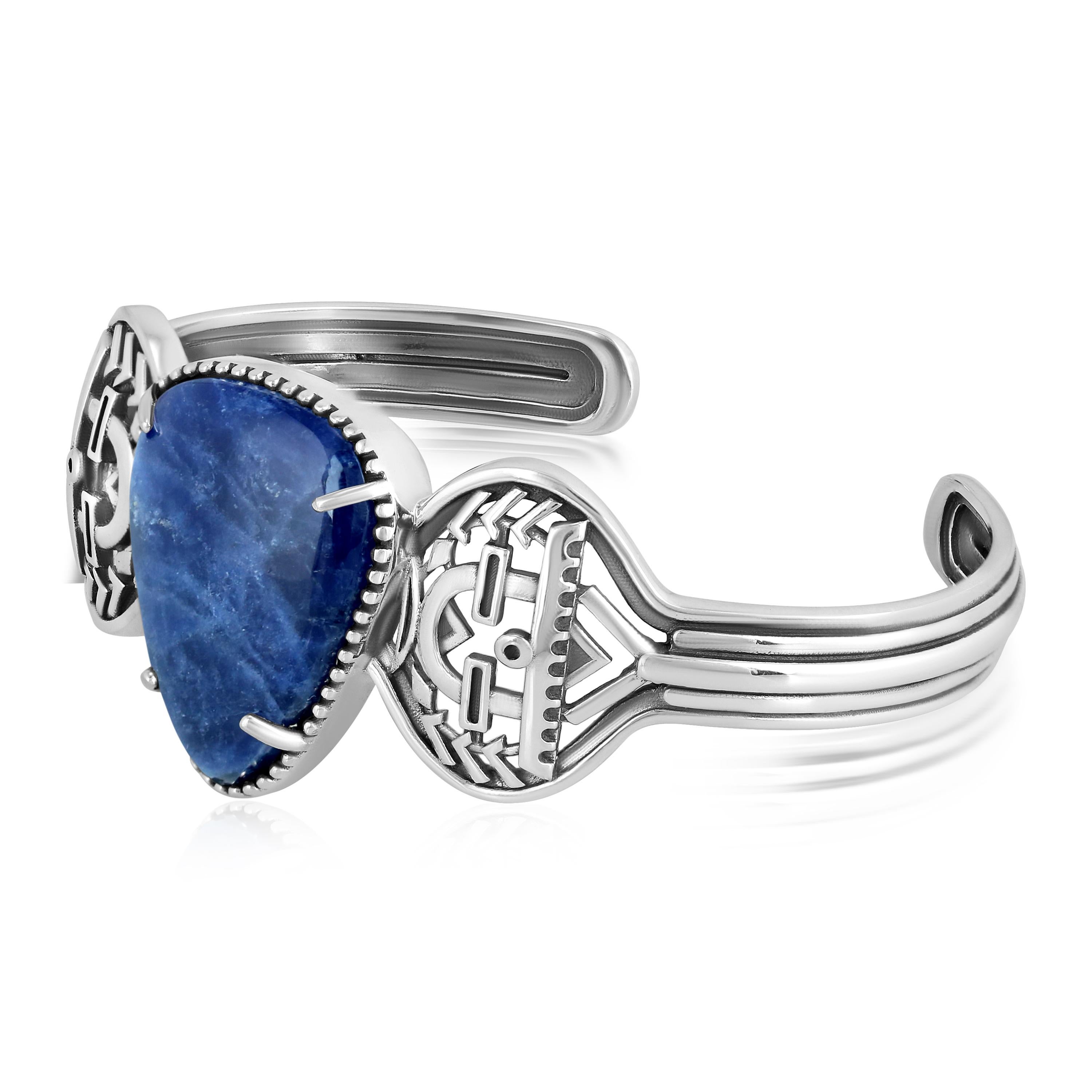 Brazalete de plata de ley con cabujón triangular de sodalita de 25x19,5 mm en el centro, engastado con cuentas; diseño Yeibichai a ambos lados; hombros estriados; acabado oxidado
La talla pequeña se ajusta a muñecas de 6,25