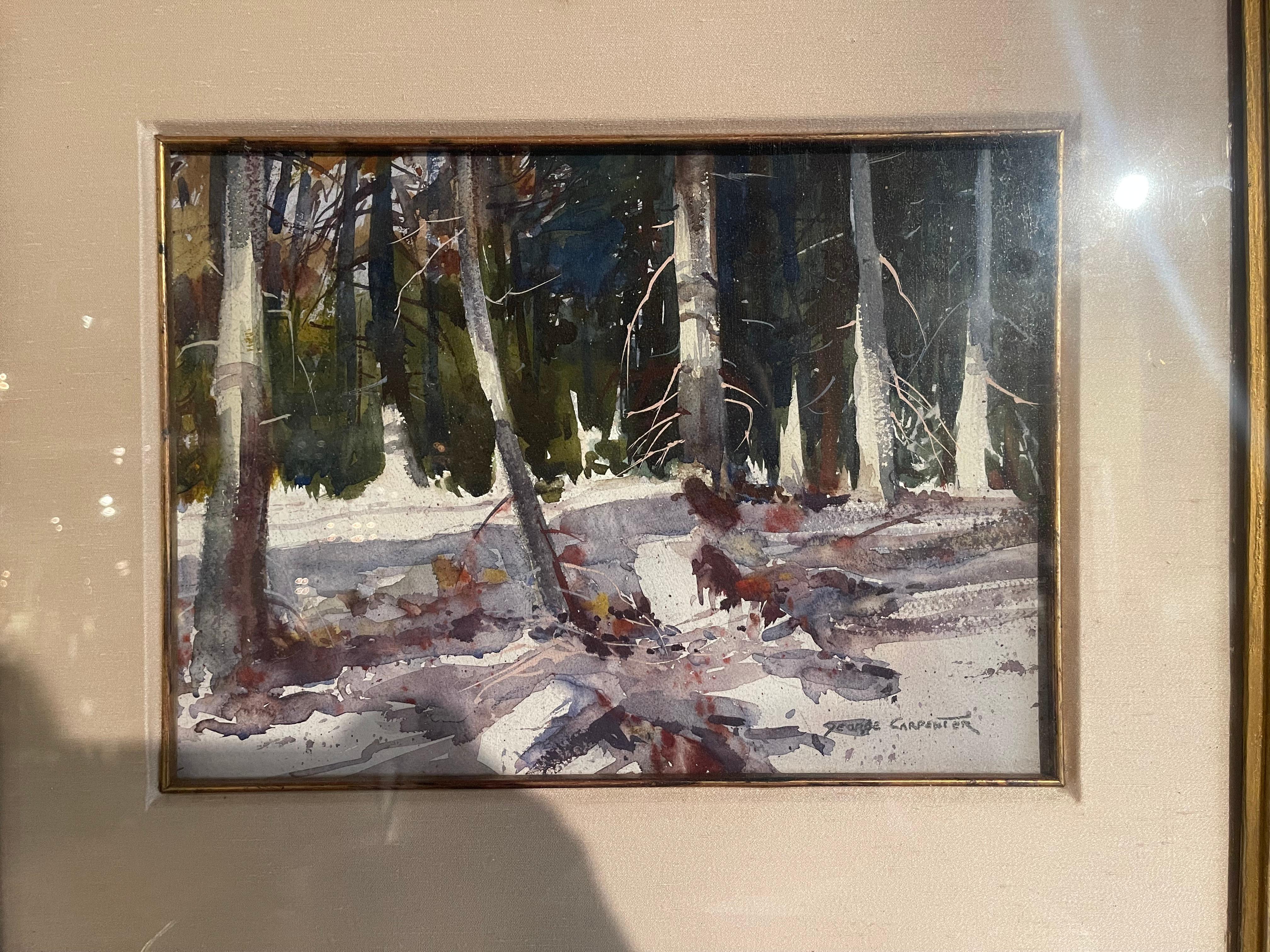 Set inside a carved gilt framed behind protective glass, this watercolor on paper painting was created circa 1970 and signed in the lower right corner by the artist, George Carpenter. The peaceful artwork has a simple composition with a thick forest