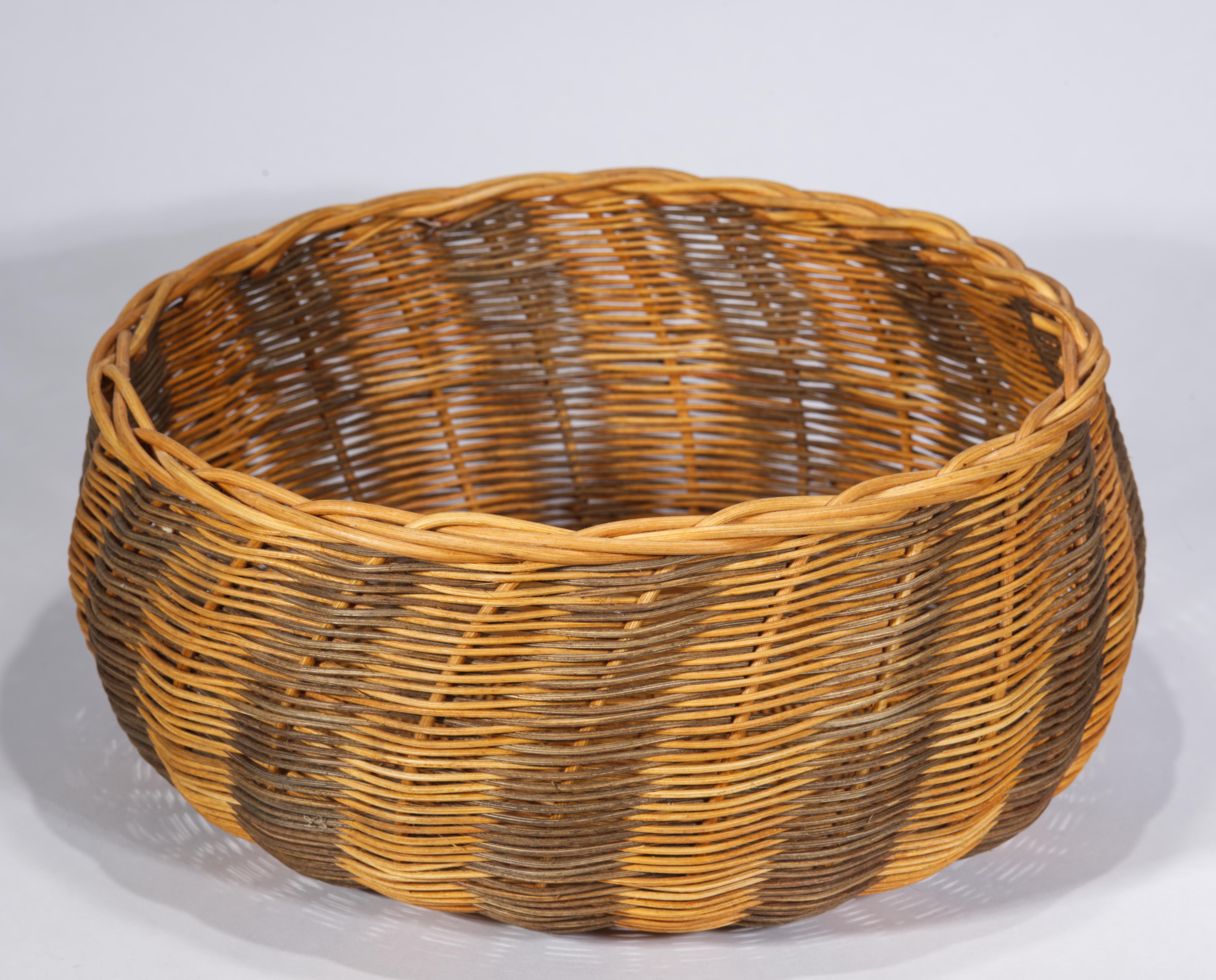 Der geflochtene Vintage-Aufbewahrungskorb hat eine traditionelle runde Form mit verstärktem Rand. Der Korpus des Korbes ist mit abstrakten geomantischen Farbblockelementen verziert, die durch die Verwendung von gefärbten Weidenstücken während des