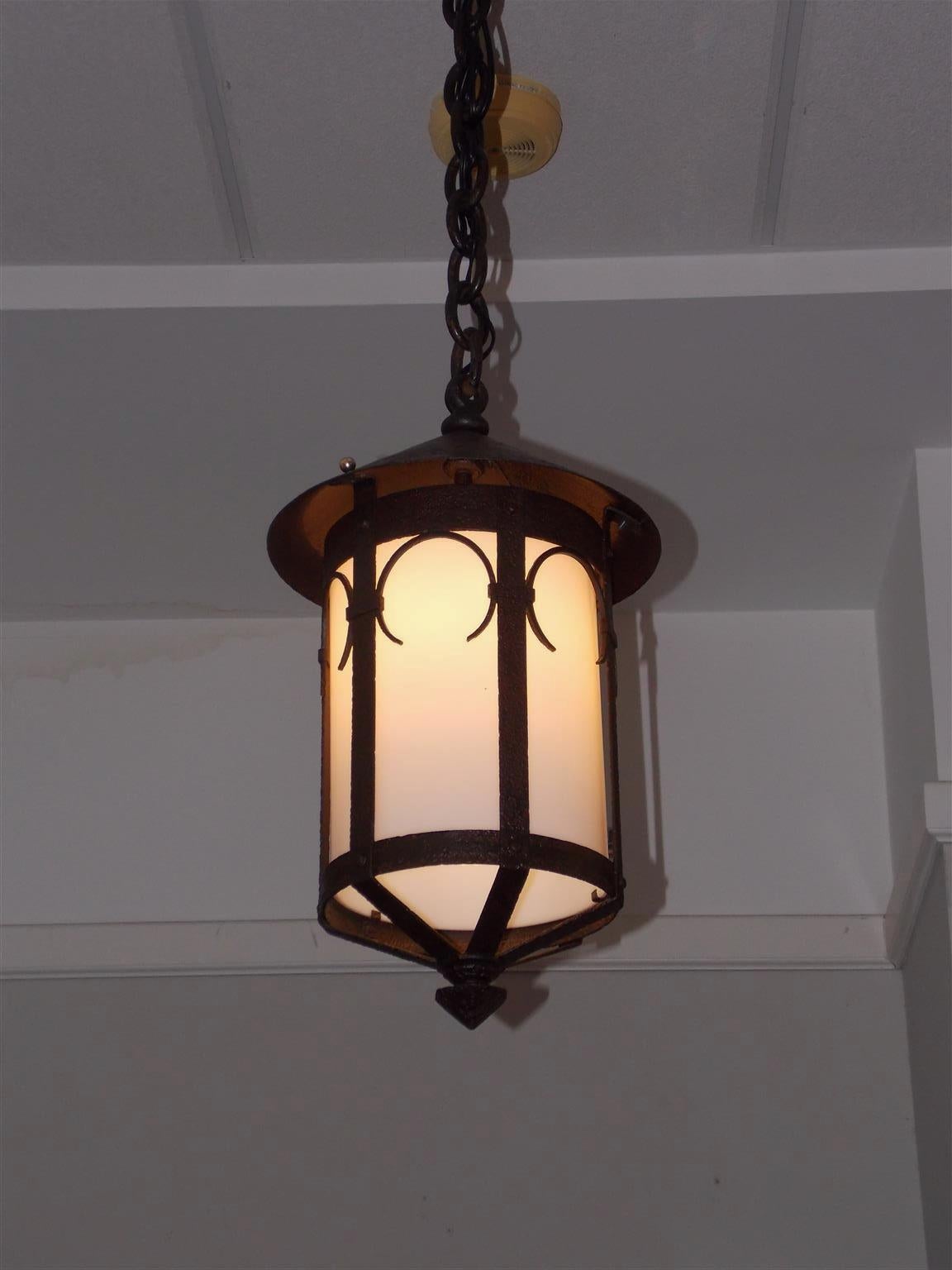 American wrought iron and milk glass hanging hall lantern with decorative arches and a centered faceted finial, Mid-19th century. Originally candle and has been electrified.