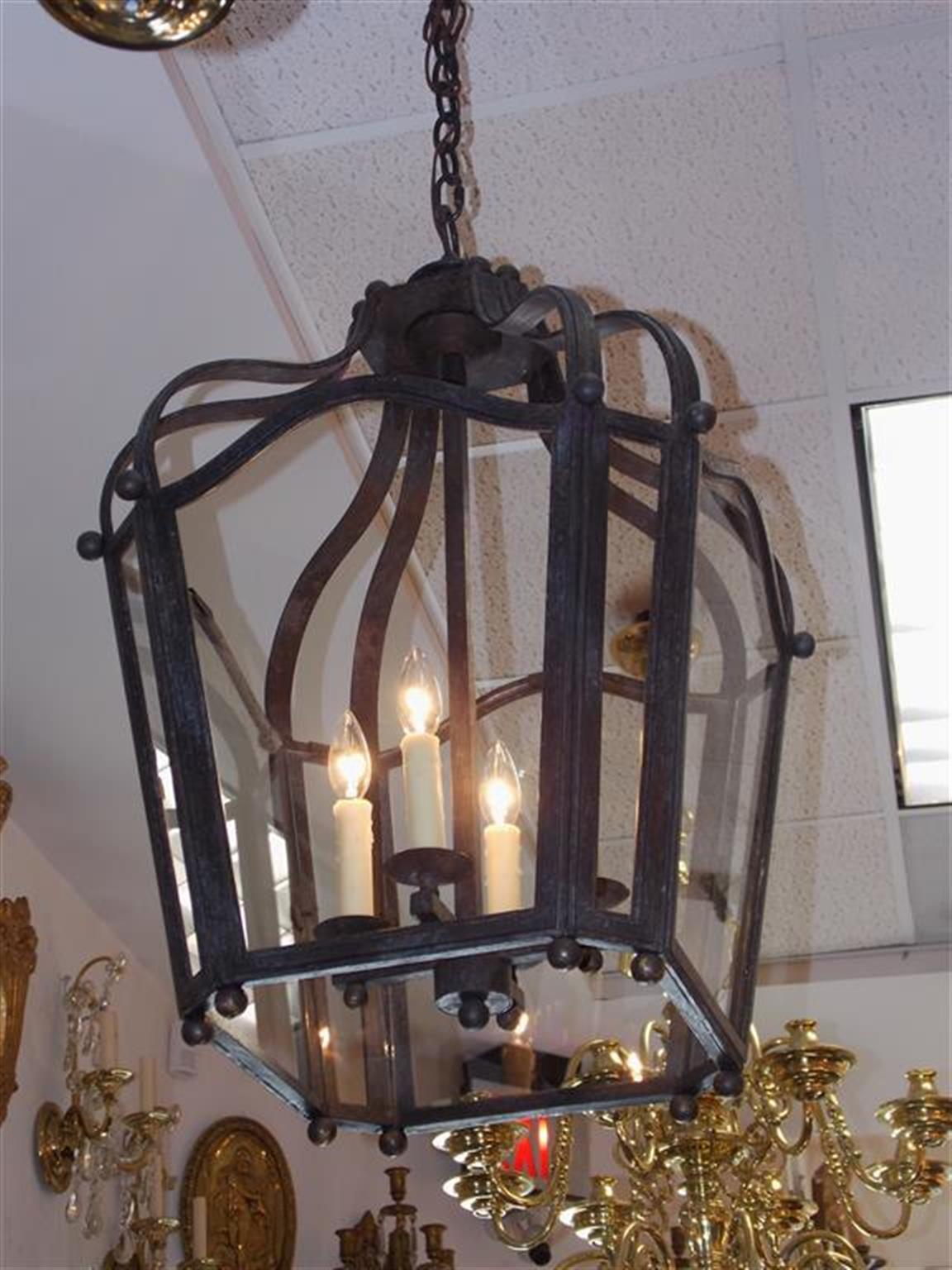 American wrought iron hanging lantern with arched scroll work, eight glass panels, four-light interior cluster, and adorned with exterior brass ball finials. Originally candle powered and has been electrified, Late 19th century