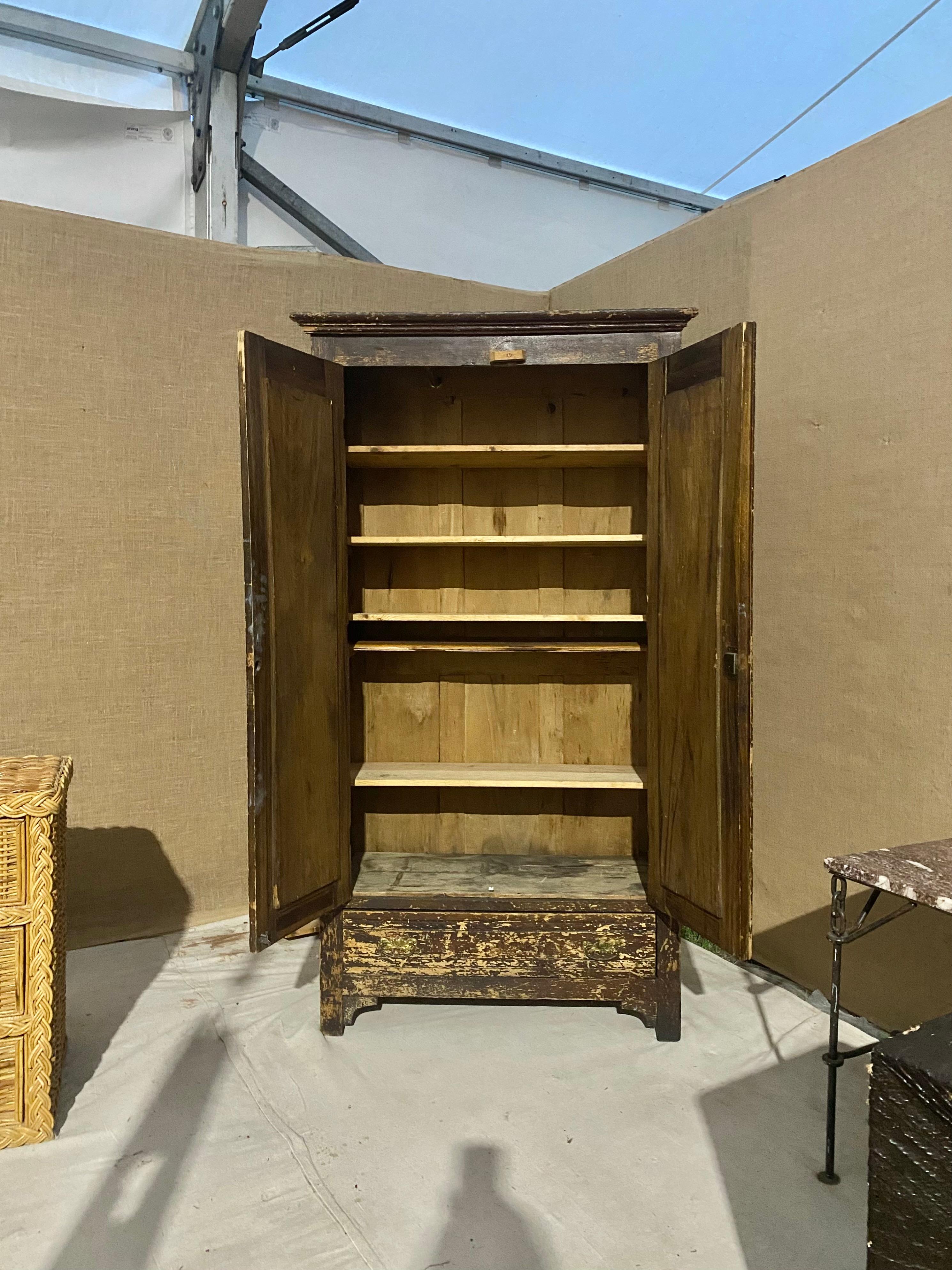 Natural patina wear patterns serve as the main decorative element to the exterior of this solid wood, American oak armoire. Recently fitted with removable natural pine shelves; original clothing bar remains (pictured). Large drawer at base; brass