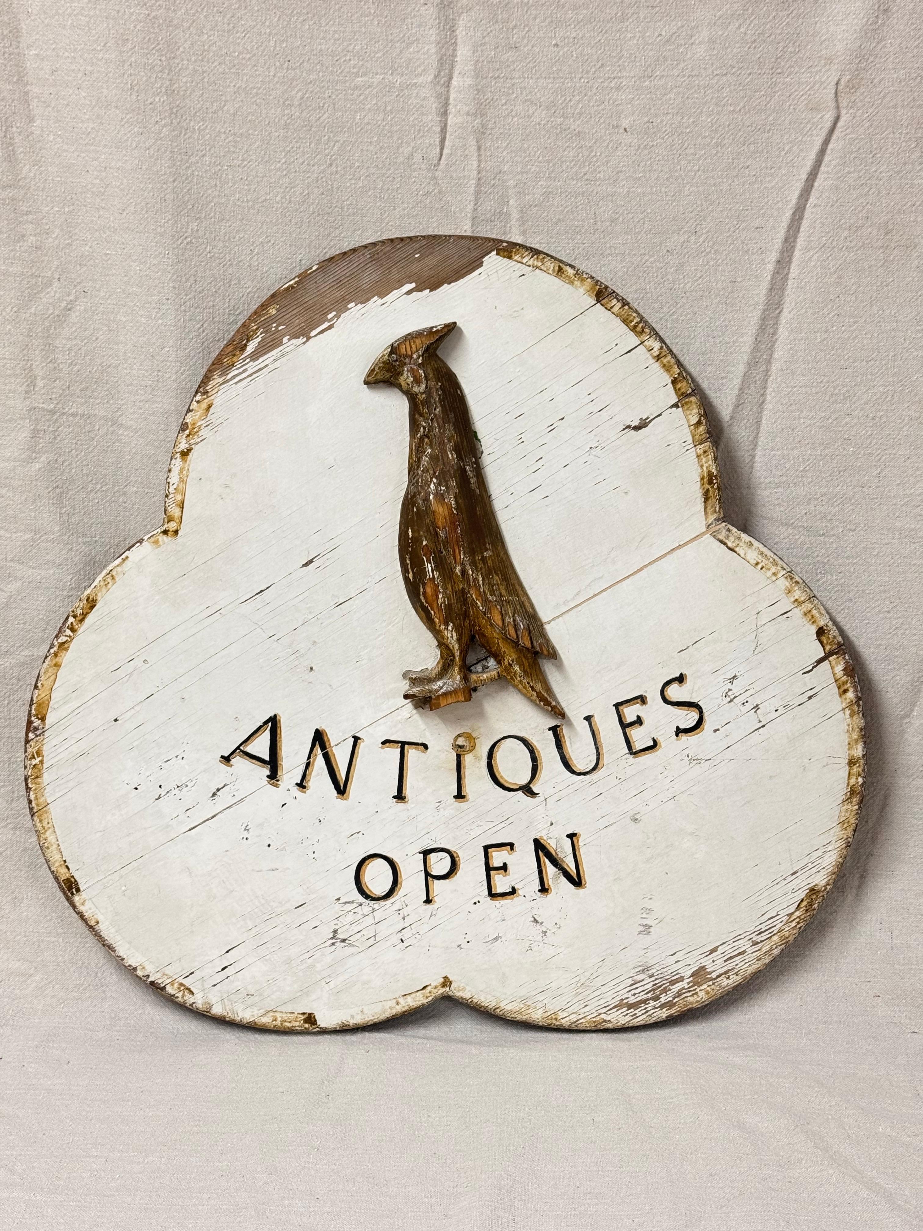 Insegna in legno intagliata a mano di un negozio antico. Insegna a forma di trifoglio in legno massiccio dipinta a mano con la scritta Antiquariato aperto. Un grazioso uccello in legno intagliato a mano come centrotavola. Grande pezzo di arte