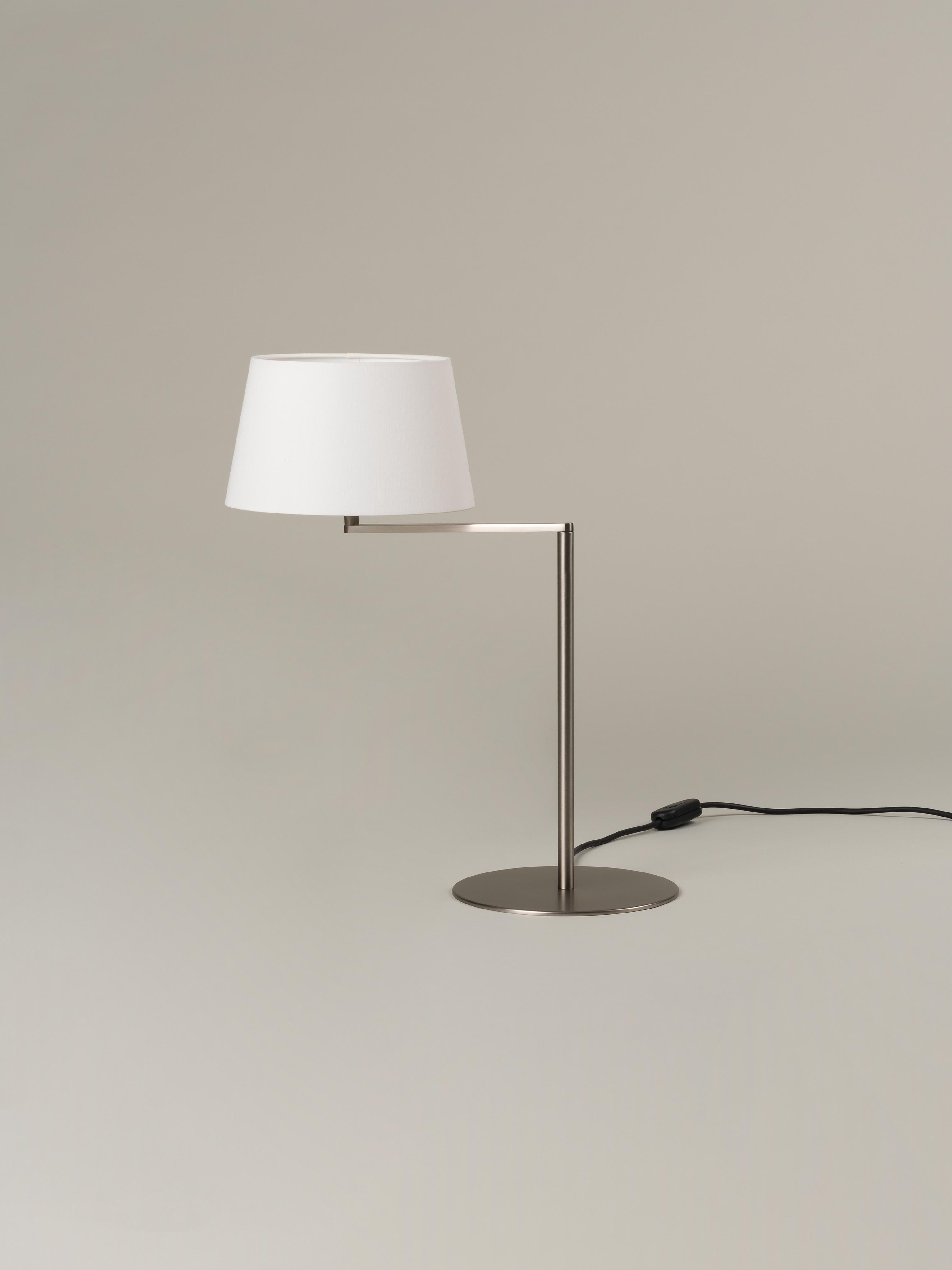 Americana table lamp by Miguel Milá
Dimensions: W 25 x D 46 x H 54 cm
Materials: Satin nickel, linen.

The Americana series is built around a satin nickel rotating arm holding an elegant white linen shade. The arm gently swivels the light nearer