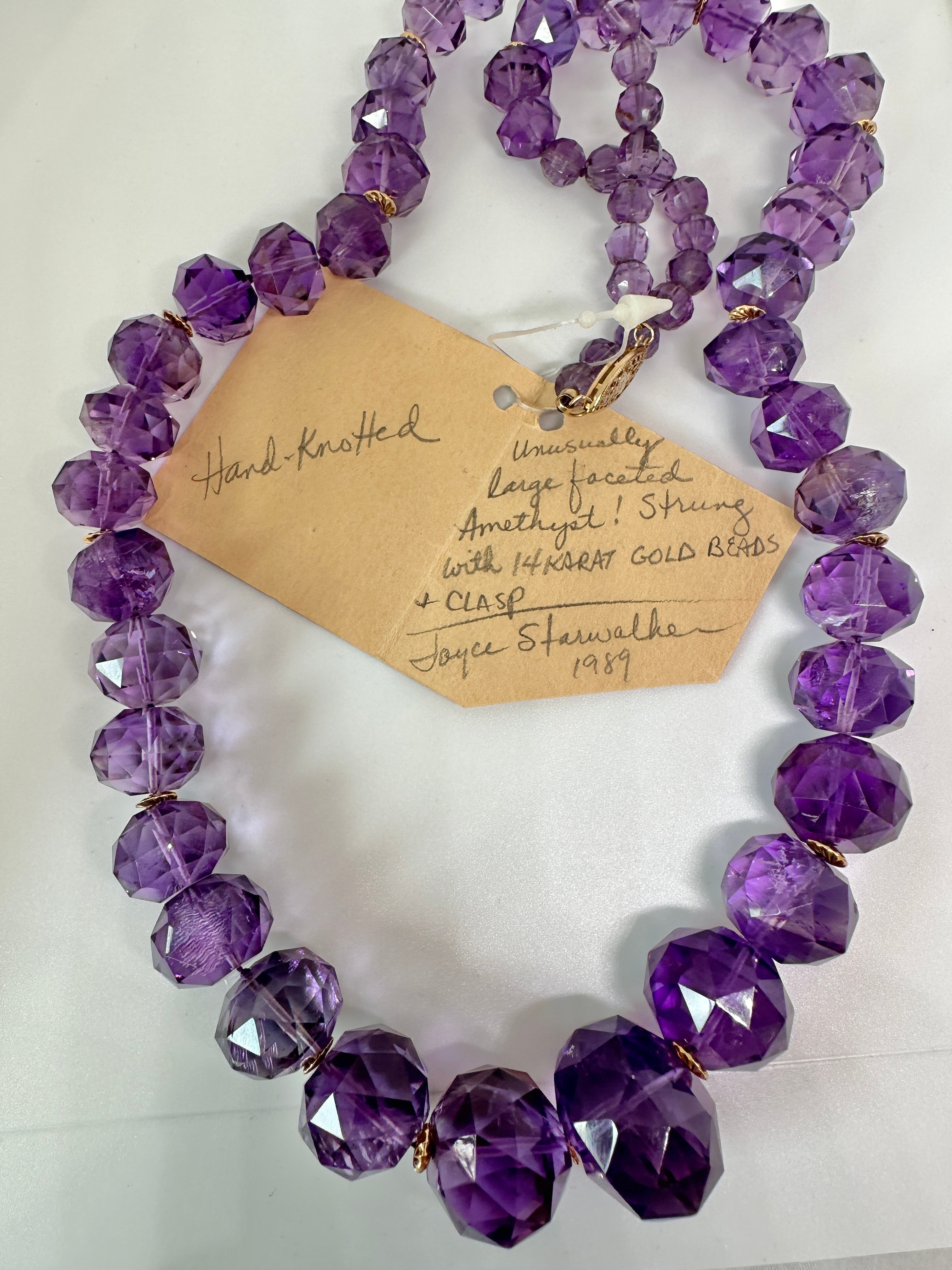 Il s'agit d'un spectaculaire collier de perles d'améthyste de 26,5 pouces avec des perles d'espacement et un fermoir en or jaune 14 carats.  Ce collier est un chef-d'œuvre de l'artiste amérindienne Joyce Starwalker et porte l'étiquette originale de