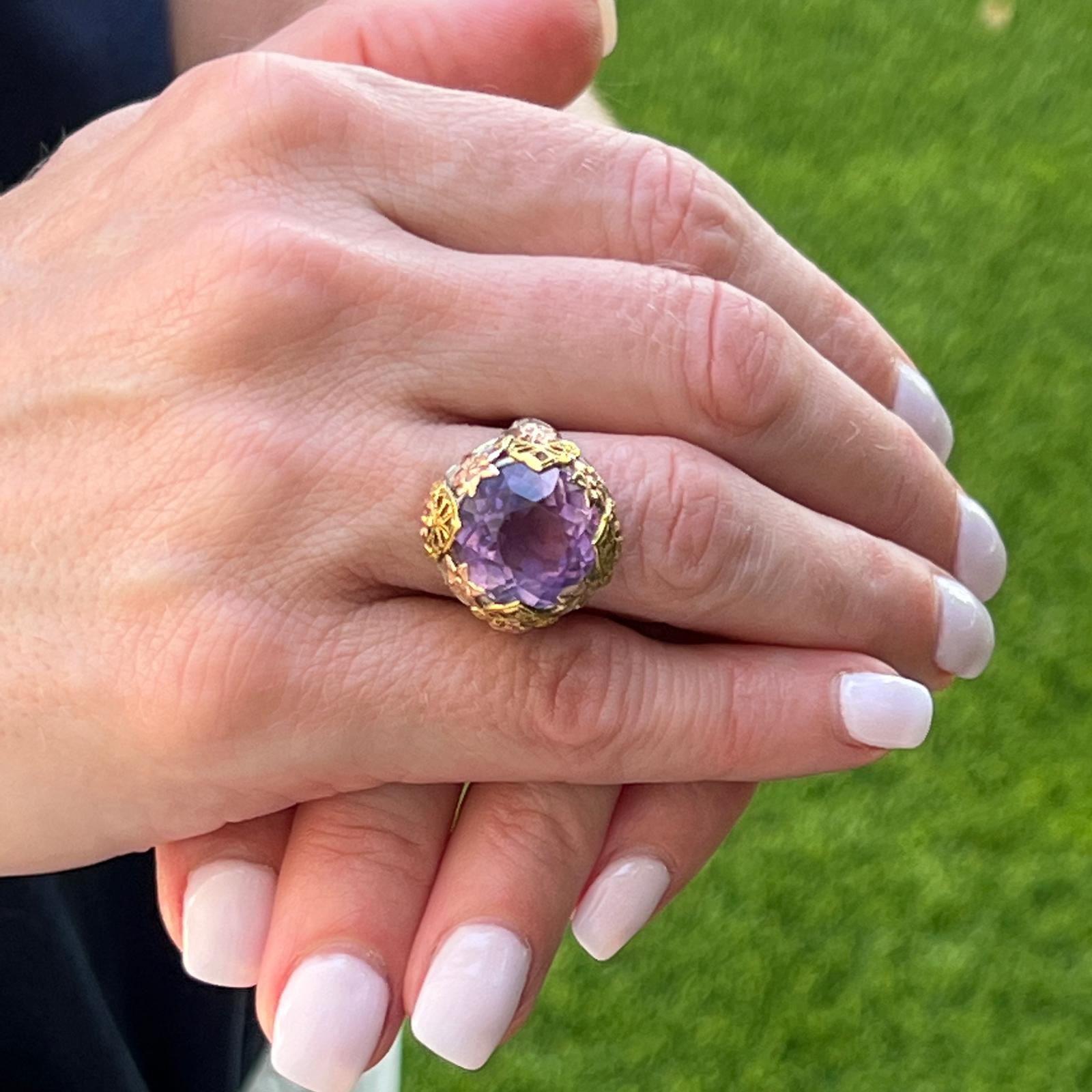 Beautiful vintage amethyst cocktail ring handcrafted in 14 karat rose, white, and yellow gold. The tri-color gold mounting features a floral motif and is set with a round faceted natural amethyst gemstone. The ring measures 20mm on top and is