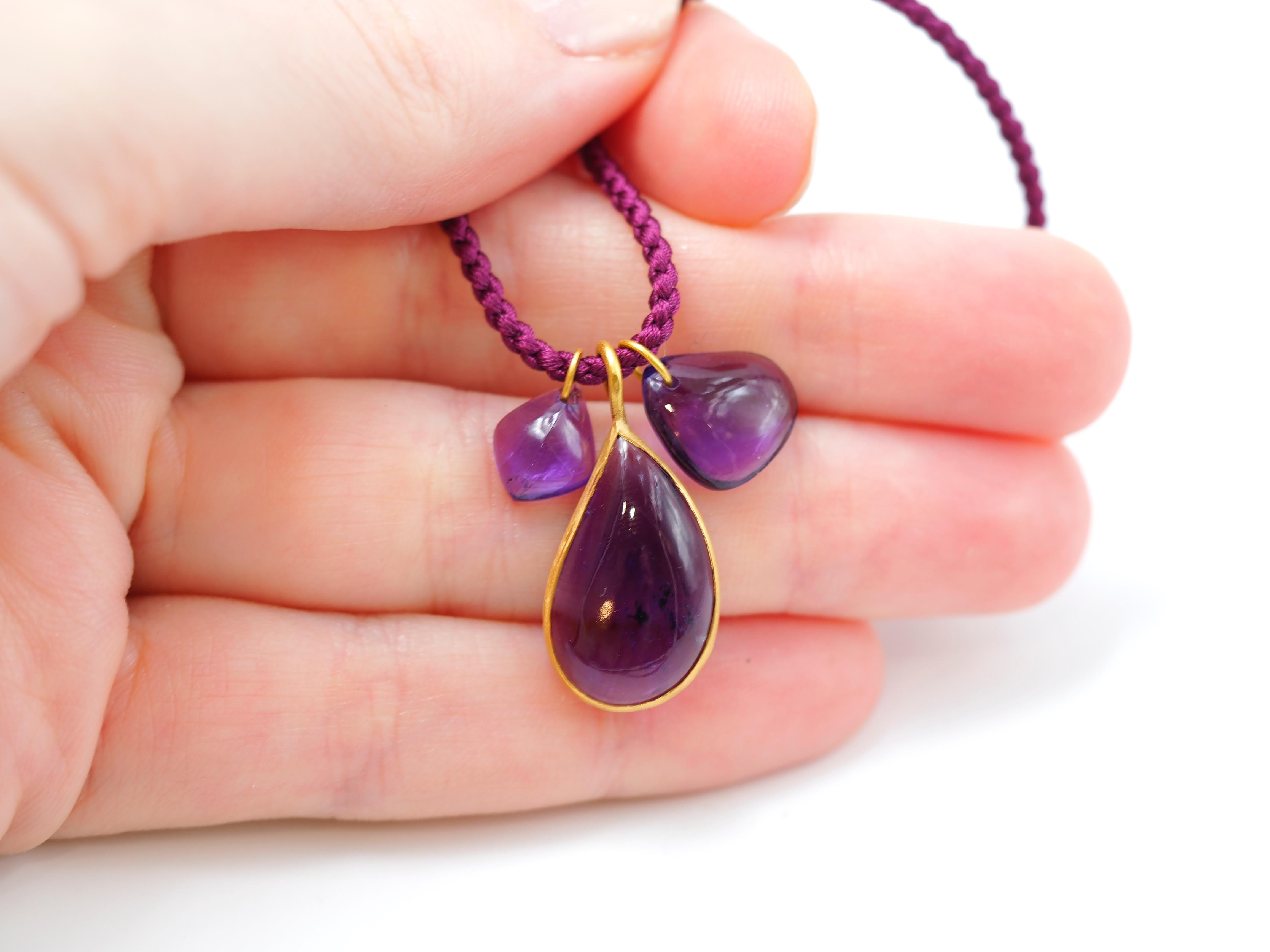 This necklace for amethyst lovers is composed of 3 pendants on a long braided silk rope:
- a large amethyst drop cabochon of 7.25 cts in gold close setting
- a small tumble heart amethyst cabochon
- a small amethyst leaf

A 22cts gold chain can also