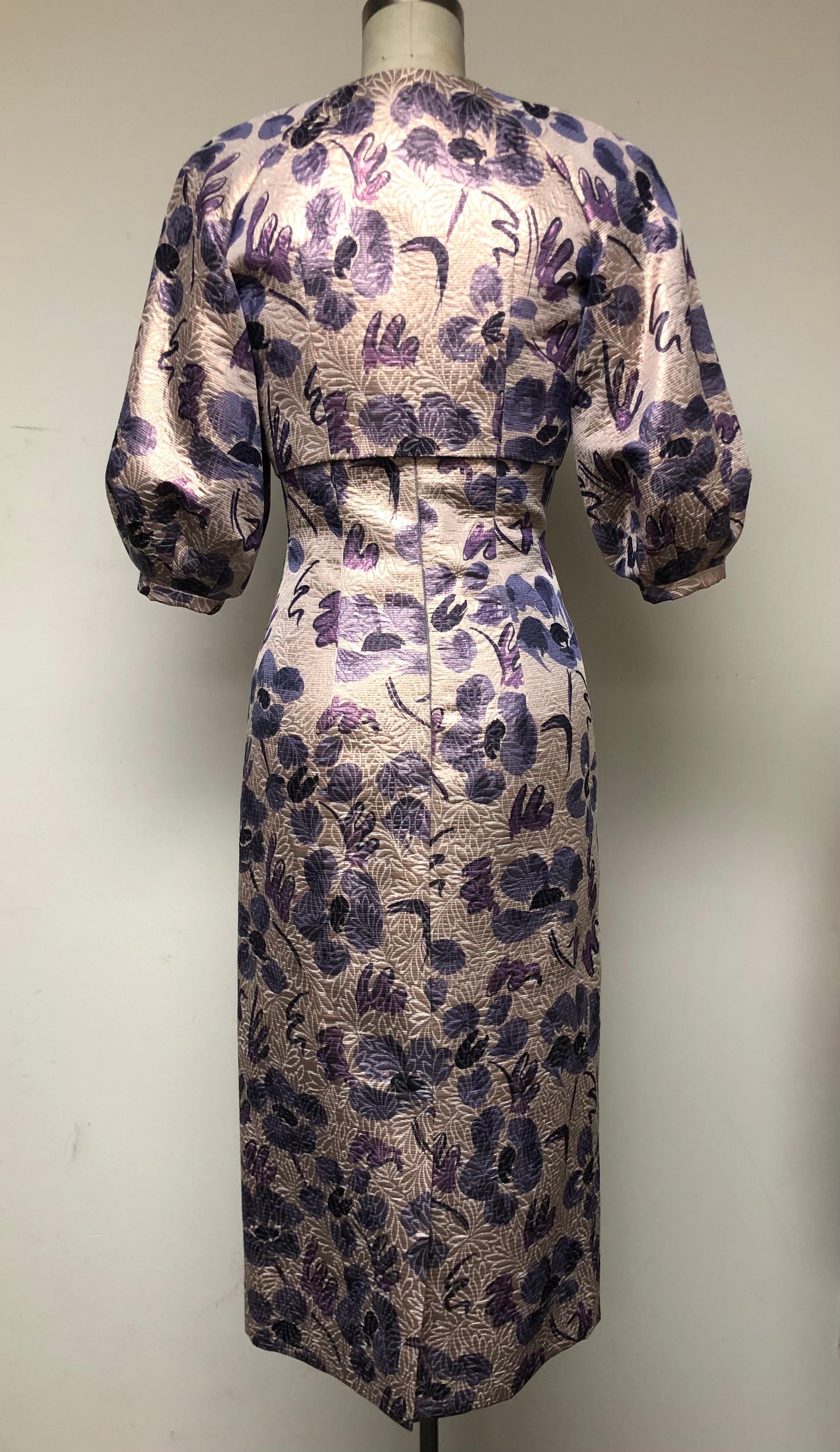 Dreamy, magical, floral for purple lovers! Whimsically abstract on a textured rose gold ground—a unique combination—this v neck high waisted slim dress with matching full sleeve bolero jacket, forms an ensemble that works well from day to evening.