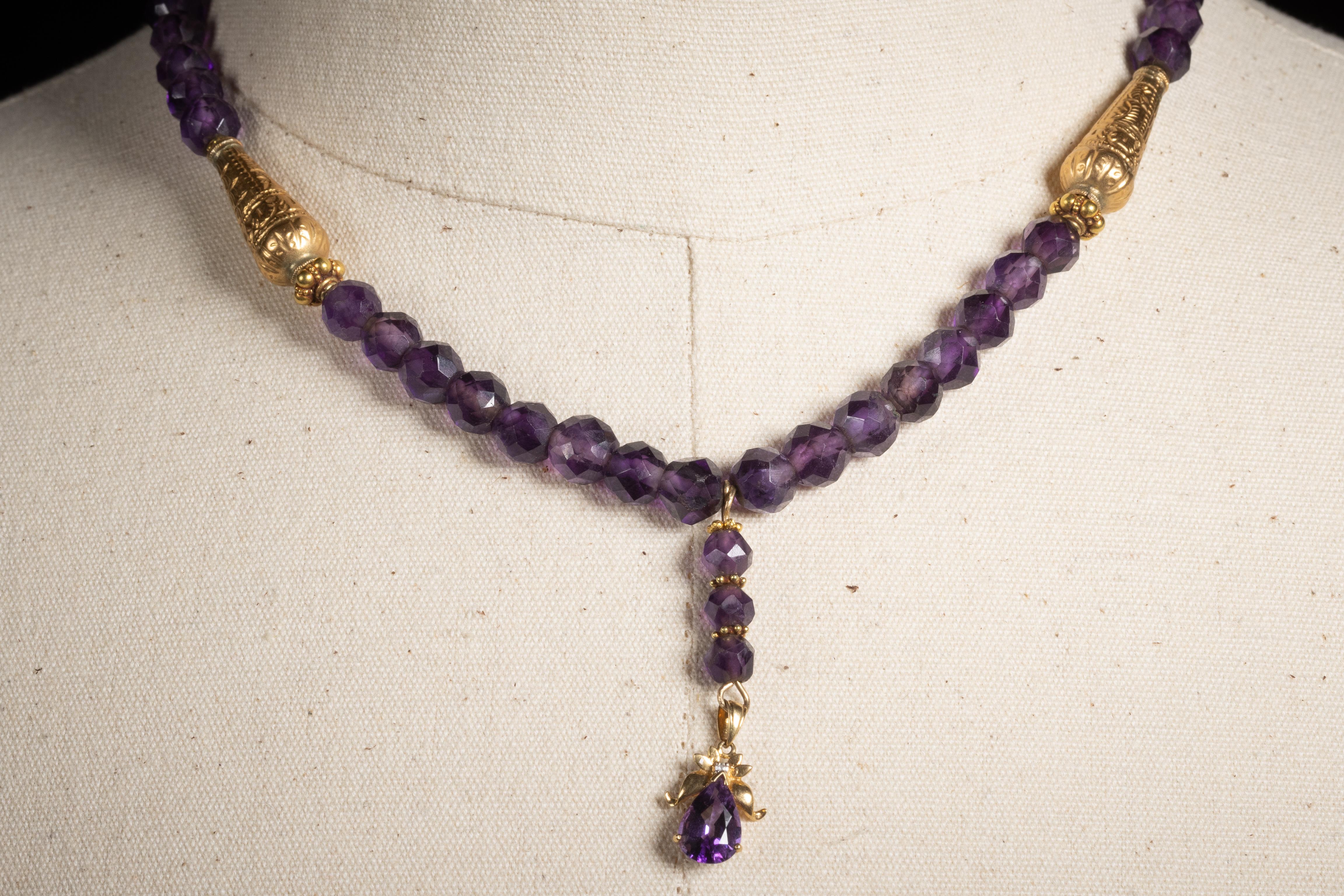 A beaded necklace of beautiful quality, faceted round amethysts with that rich, deep purple.  Just below the collar bone, are two 22K gold embossed beads.  The 1 1/2