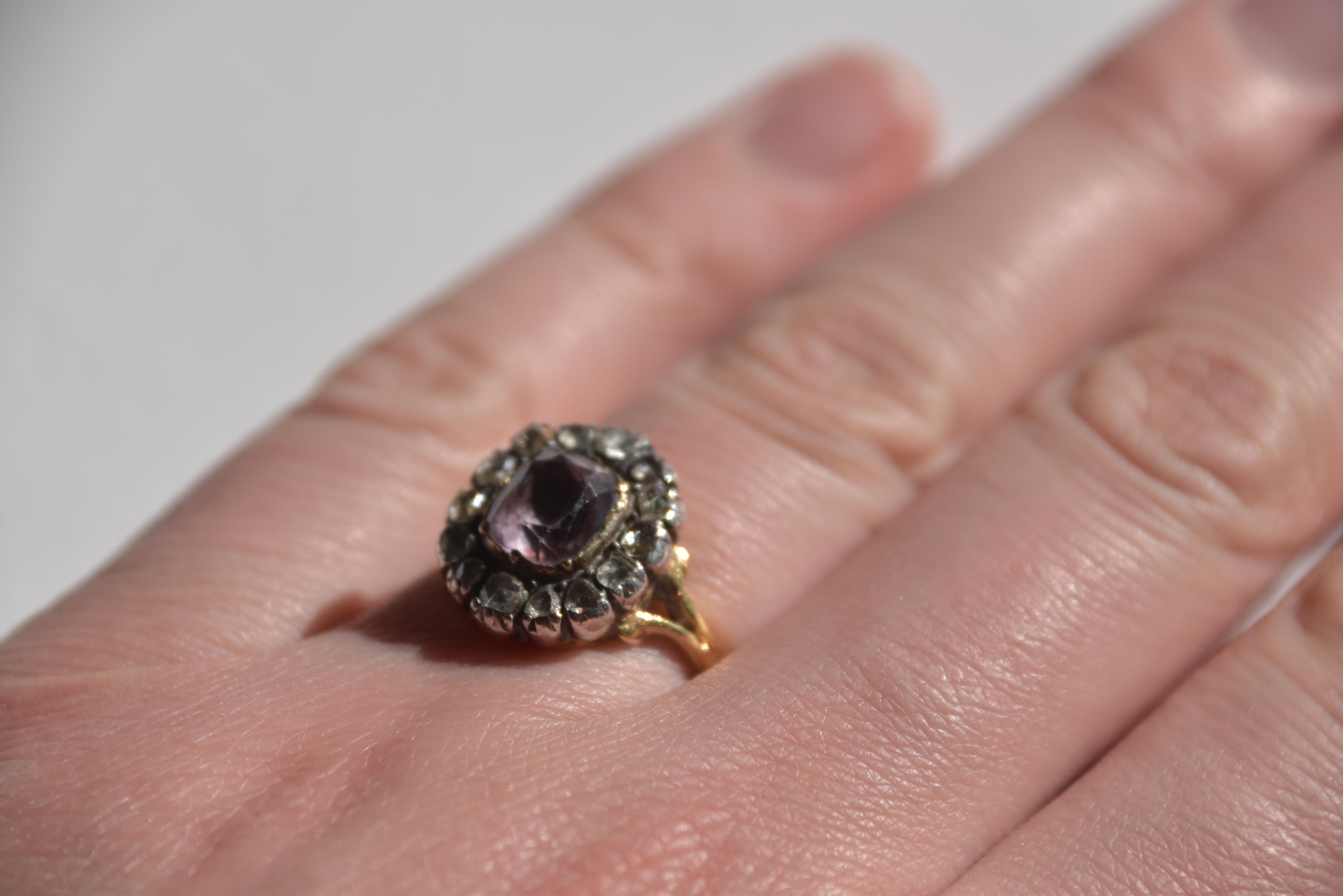 Anello con ametista e diamanti a grappolo, inizio XIX secolo, con ametista a forma di cuscino circondata da diamanti taglio rosa, in argento e oro, con montatura chiusa, misura K, punzonato.