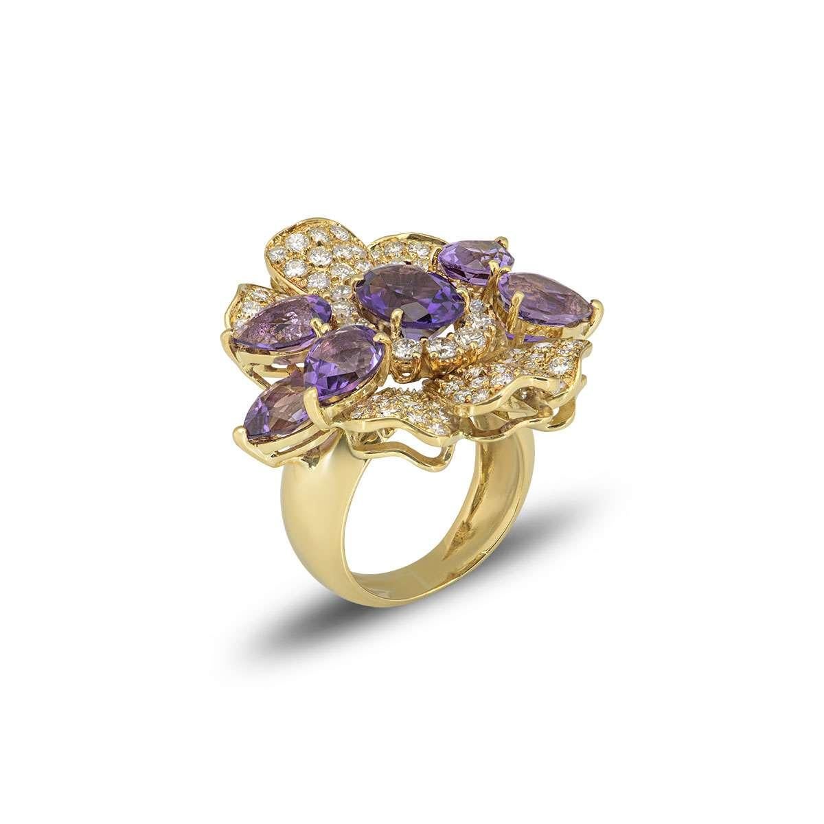 An 18k yellow gold floral style dress ring. The ring is set with 6 pear cut amethyst petals and 6 yellow gold diamond set petals, with an oval amethyst in the centre complemented by a diamond halo. The round brilliant cut diamonds have a total