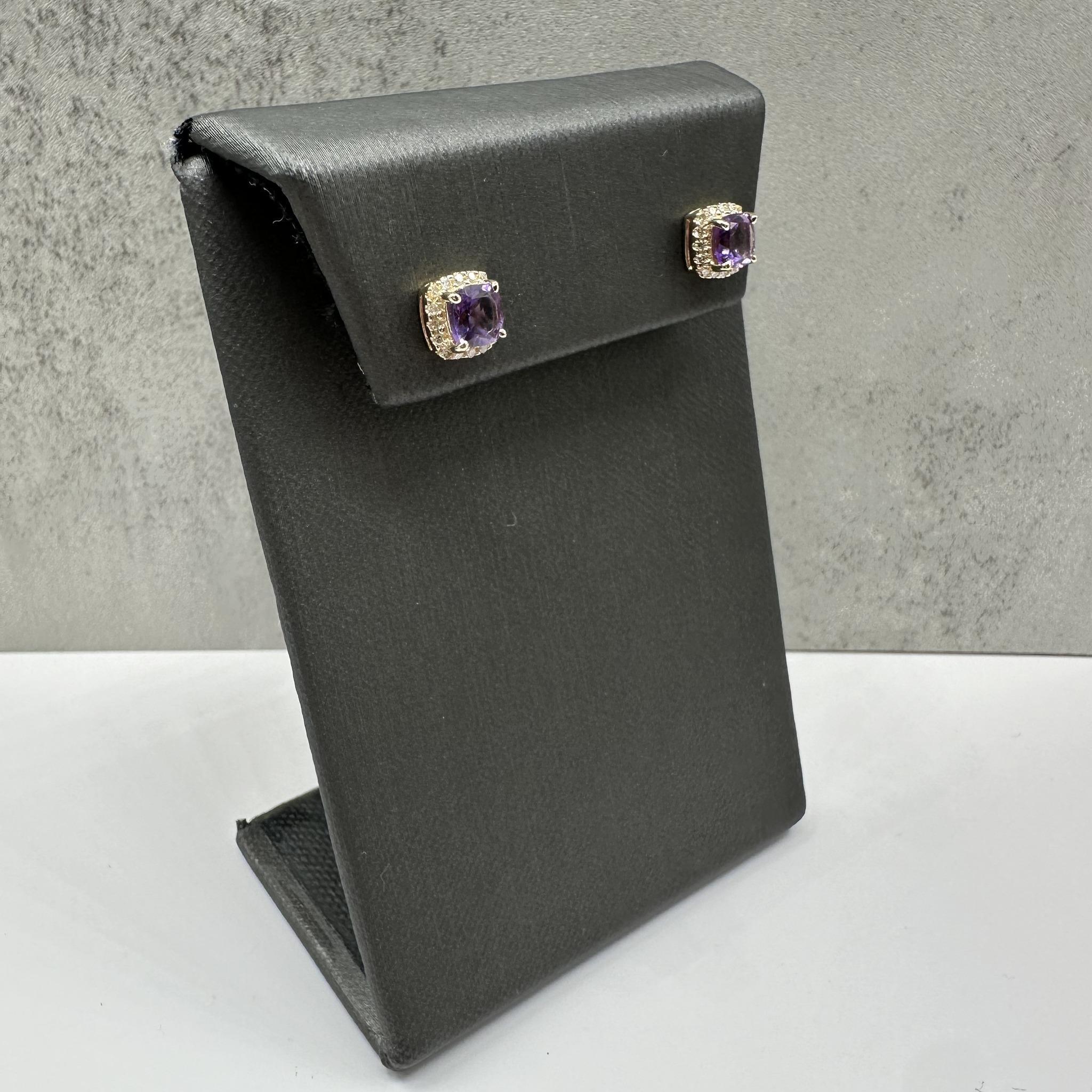 Ces élégantes boucles d'oreilles en or jaune 10kt ornées d'améthystes et de diamants présentent deux améthystes de 5 mm de diamètre taillées en coussin, magnifiquement complétées par 0,15 carats de diamants ronds de taille unique SI2-I1. La riche