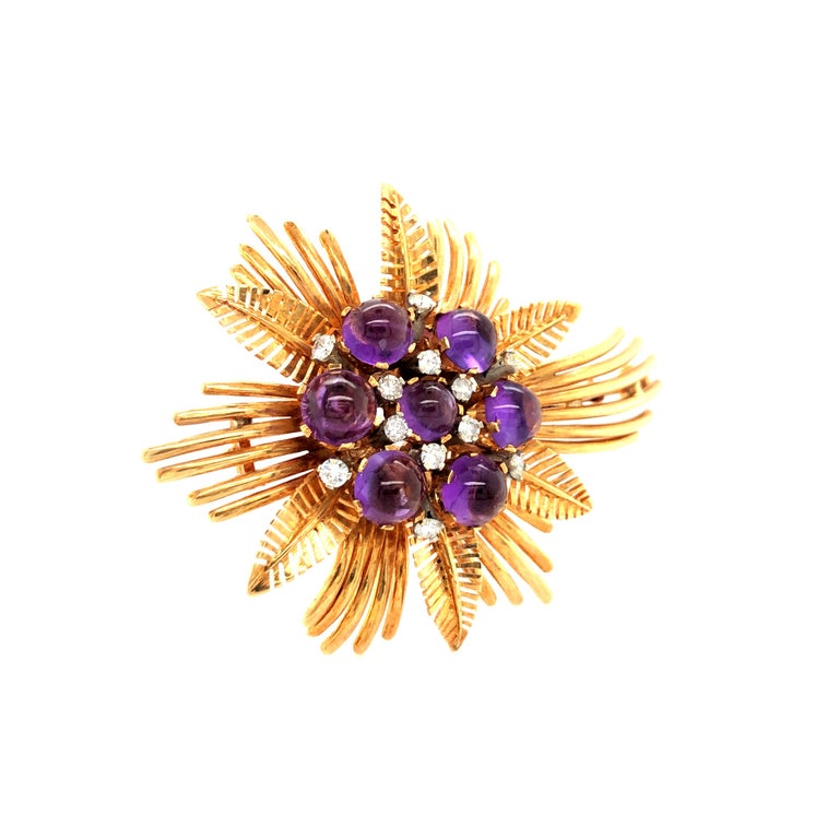 During the 1940ies opulent flower heads, set with coloured gemstones in elaborate designs were a must have. 
Here we have a very cool example, a mix of tropical leaves and a falling star.
The purple colour of the 7 cabochon cut amethysts, goes very